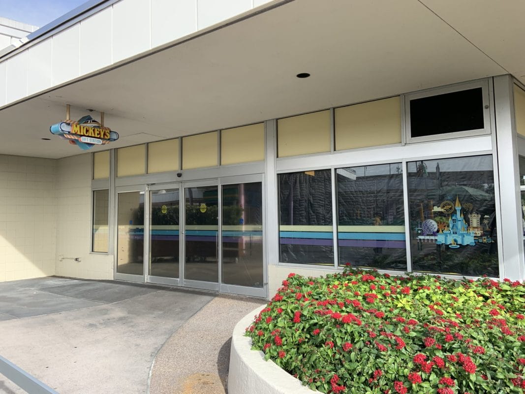 Closed storefront with a Mickey’s sign above glass doors, near a flower bed at Disney Transportation and Ticket Center
