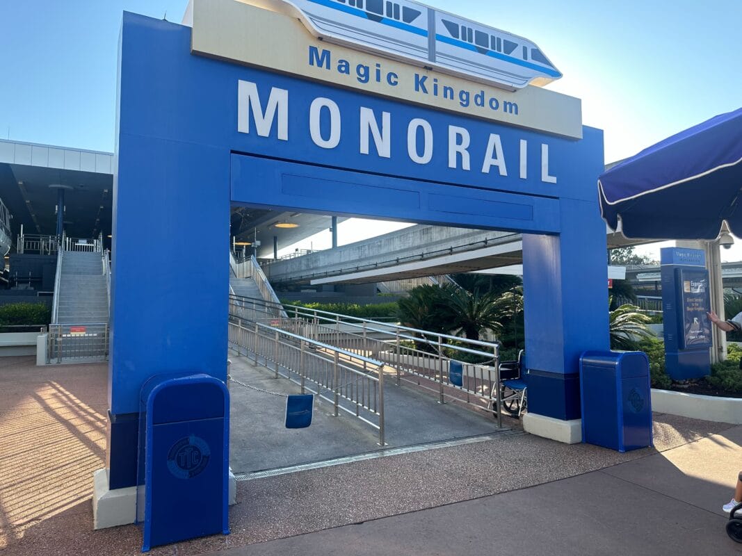 Blue entrance archway labeled “MONORAIL” and “Magic Kingdom” at the Disney Transportation Ticket Center, ramps lead to the station.