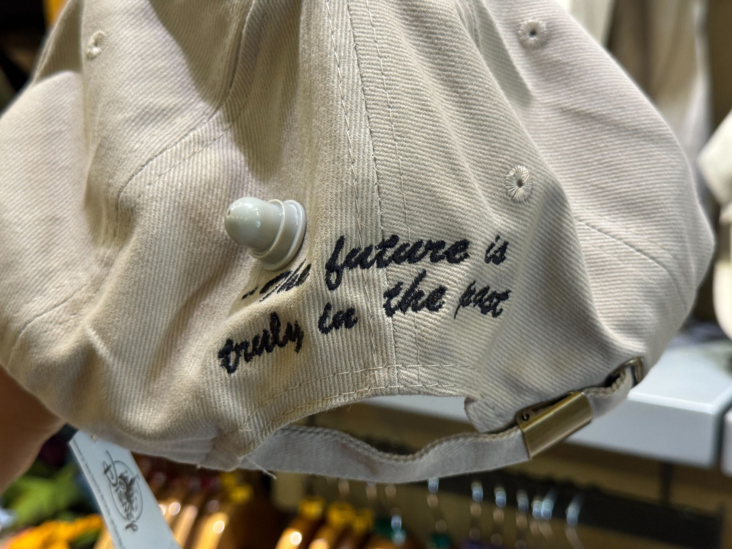 Close-up of a beige cap with black text reading, "The future is truly in the hat," and a security tag attached.