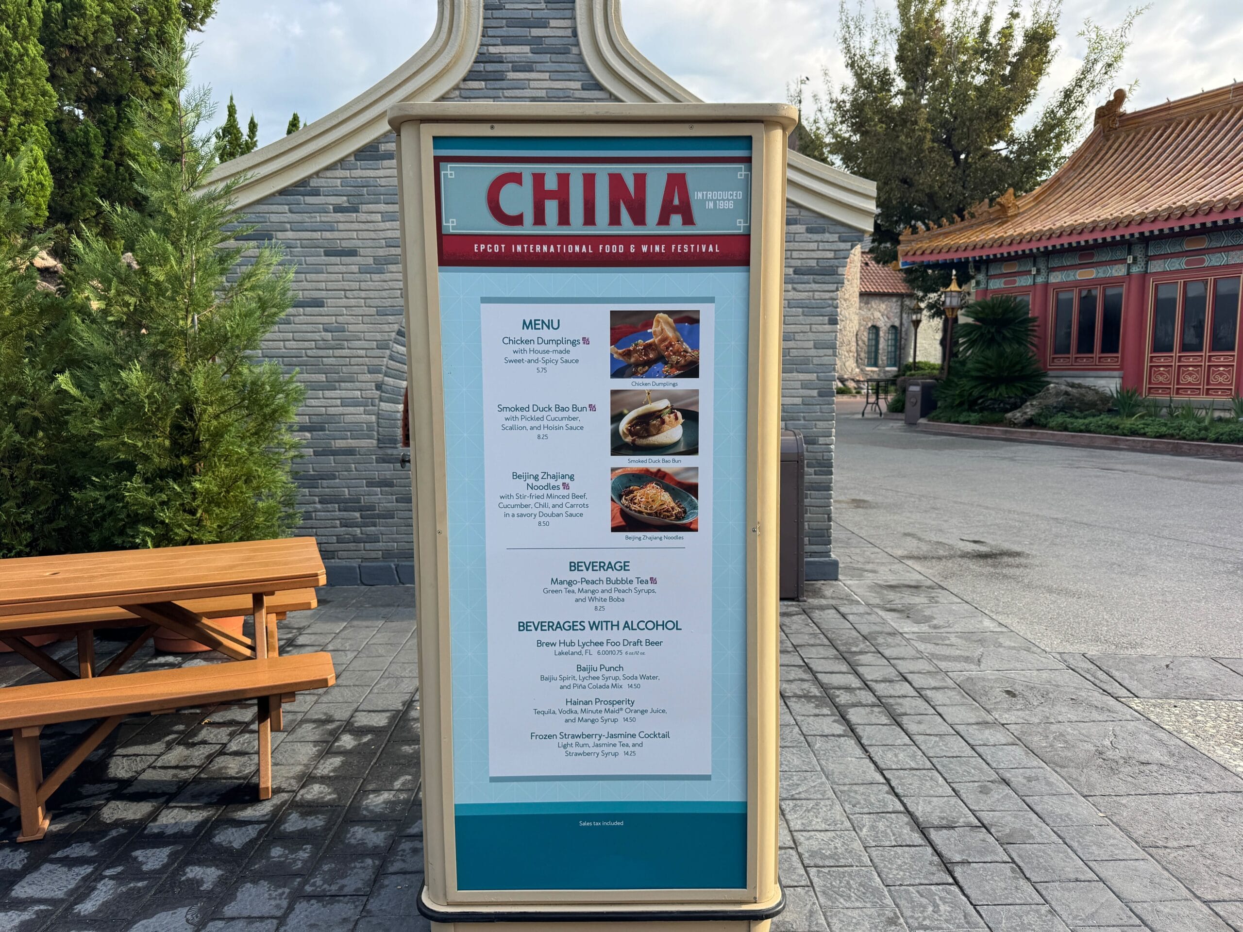 Outdoor Food & Wine menu board for the China pavilion at a food festival, set against traditional buildings in the background.