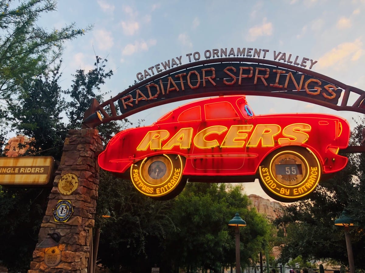 Neon sign shaped like a red car reads “Radiator Springs Racers,” currently closed for refurbishment at the park entrance.