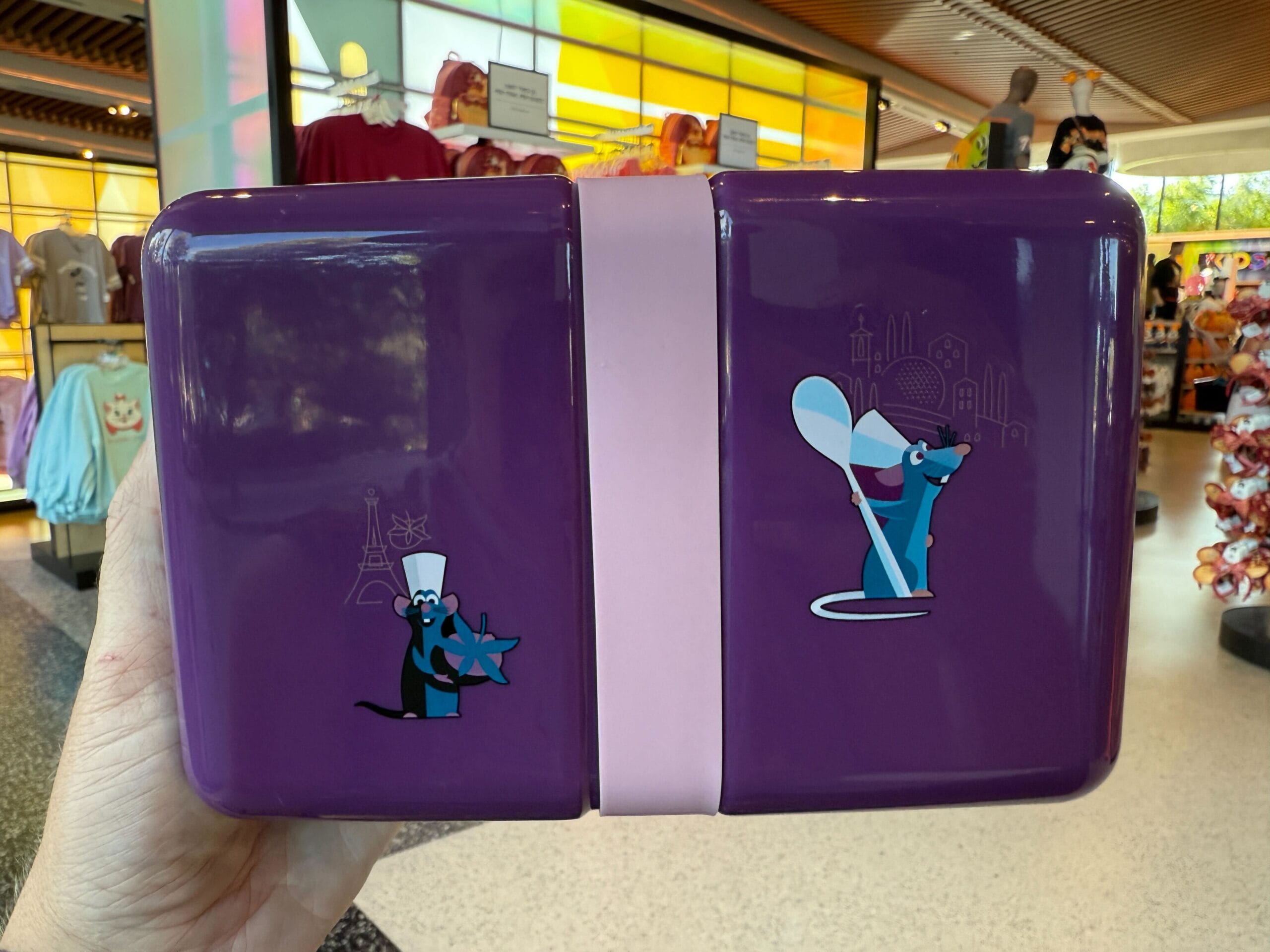 A purple lunchbox from the 2025 EPCOT Food & Wine Festival with two cartoon chef rats, one holding cheese, one a spoon.
