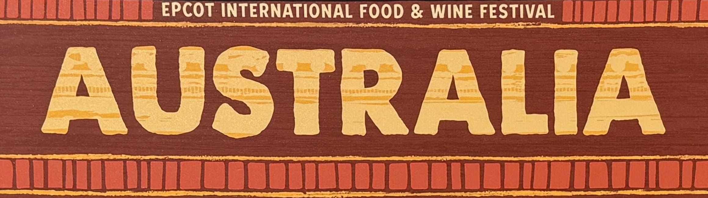 Sign reading "Australia EPCOT International Food & Wine Festival" with a brown and yellow decorative border.