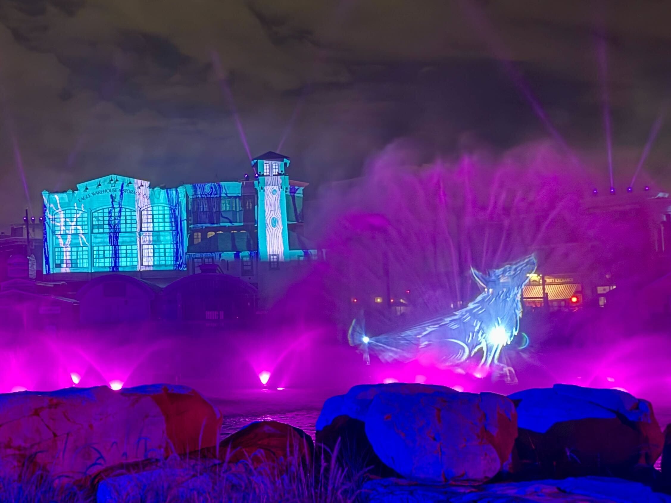 A Lagoon Show at Halloween Horror Nights 2025 features a glowing wolf, purple lights, and a lit-up building at night.