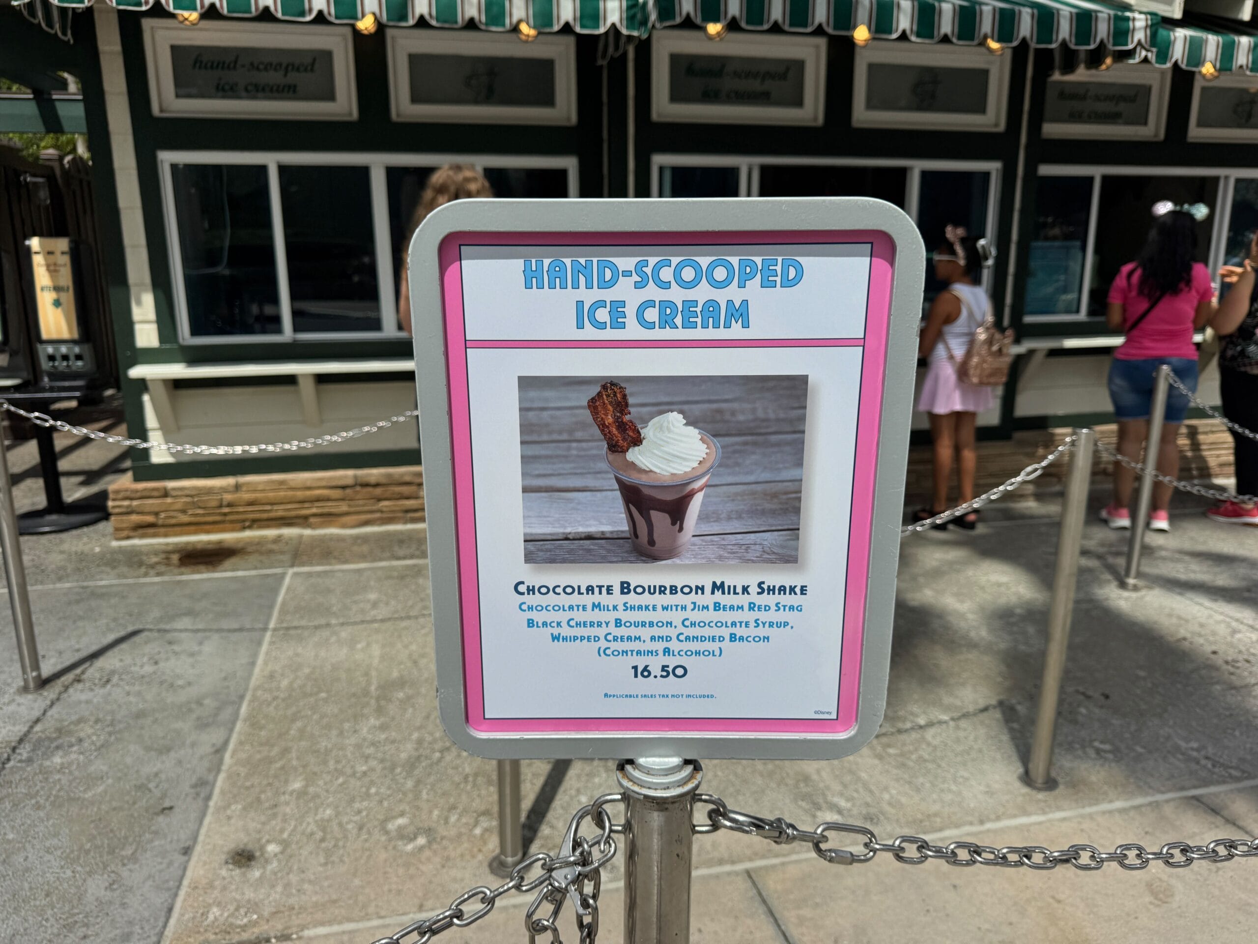 Sign promoting a Chocolate Bourbon Milk Shake with bacon at Hollywood Scoops with people waiting in line behind.