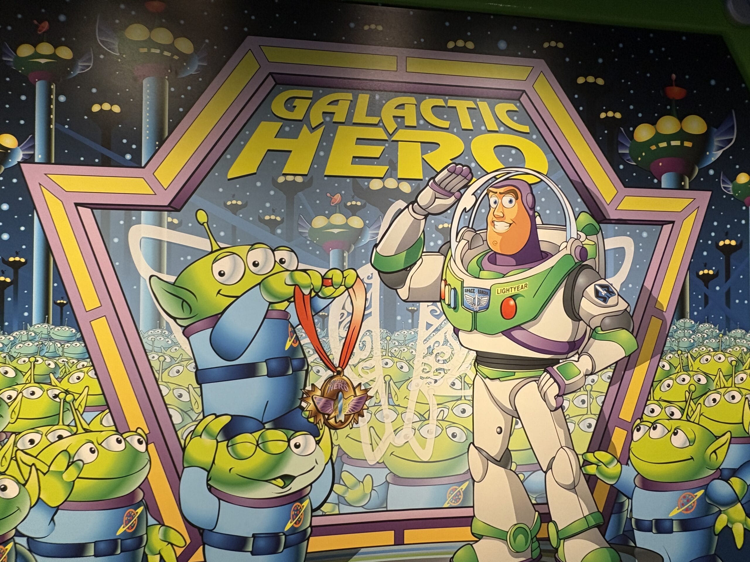Buzz Lightyear and aliens pose by a "Galactic Hero" sign from Buzz Lightyear’s Space Ranger Spin before its major overhaul.