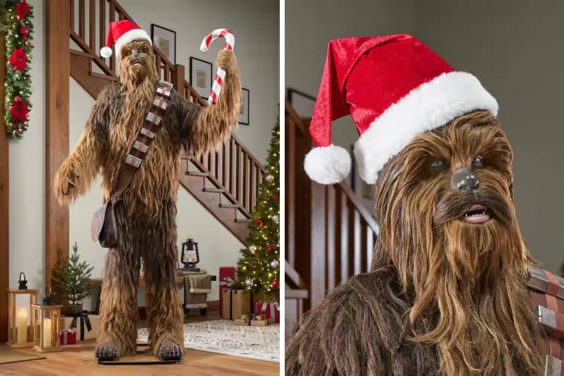 A Chewbacca animatronic figure wearing a Santa hat and holding a candy cane stands in a space decorated for the holidays.