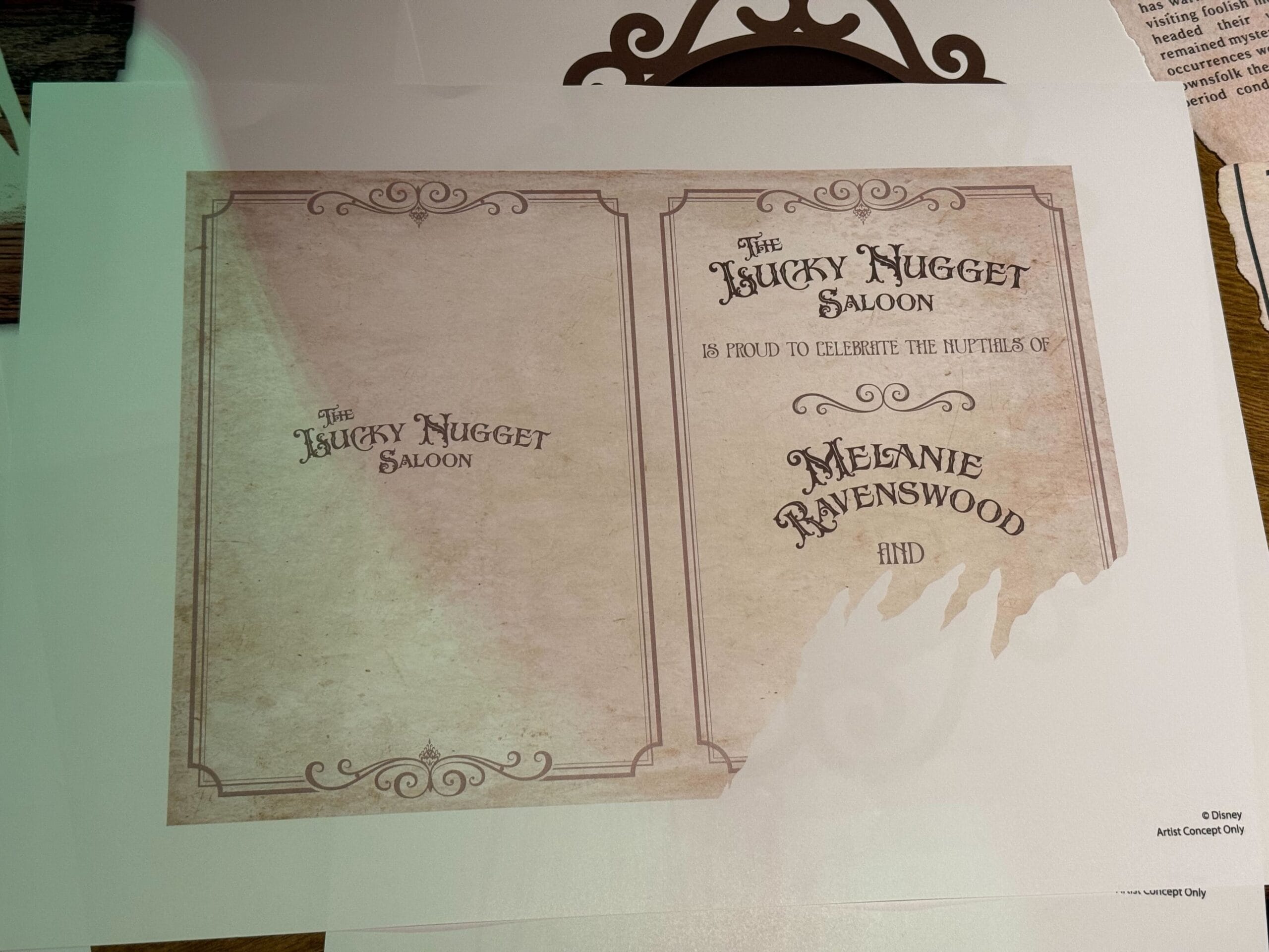 An invitation from The Unlucky Nugget Saloon, celebrating Melanie Ravenswood of Phantom Manor, with ornate border and torn corner.