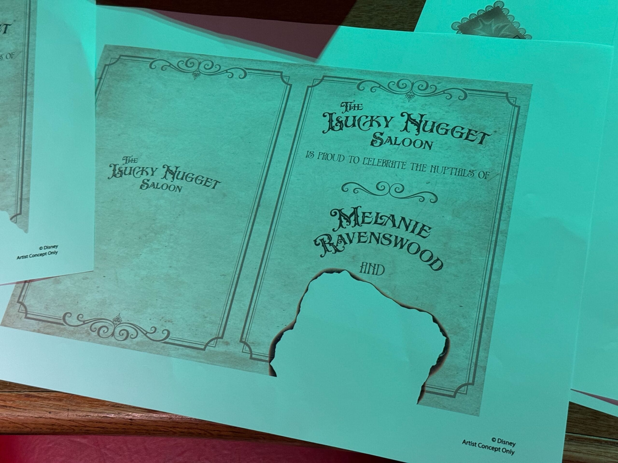 A printed wedding invite for Melanie Ravenswood at The Lucky Nugget Saloon, with a Phantom Manor Halloween overlay.