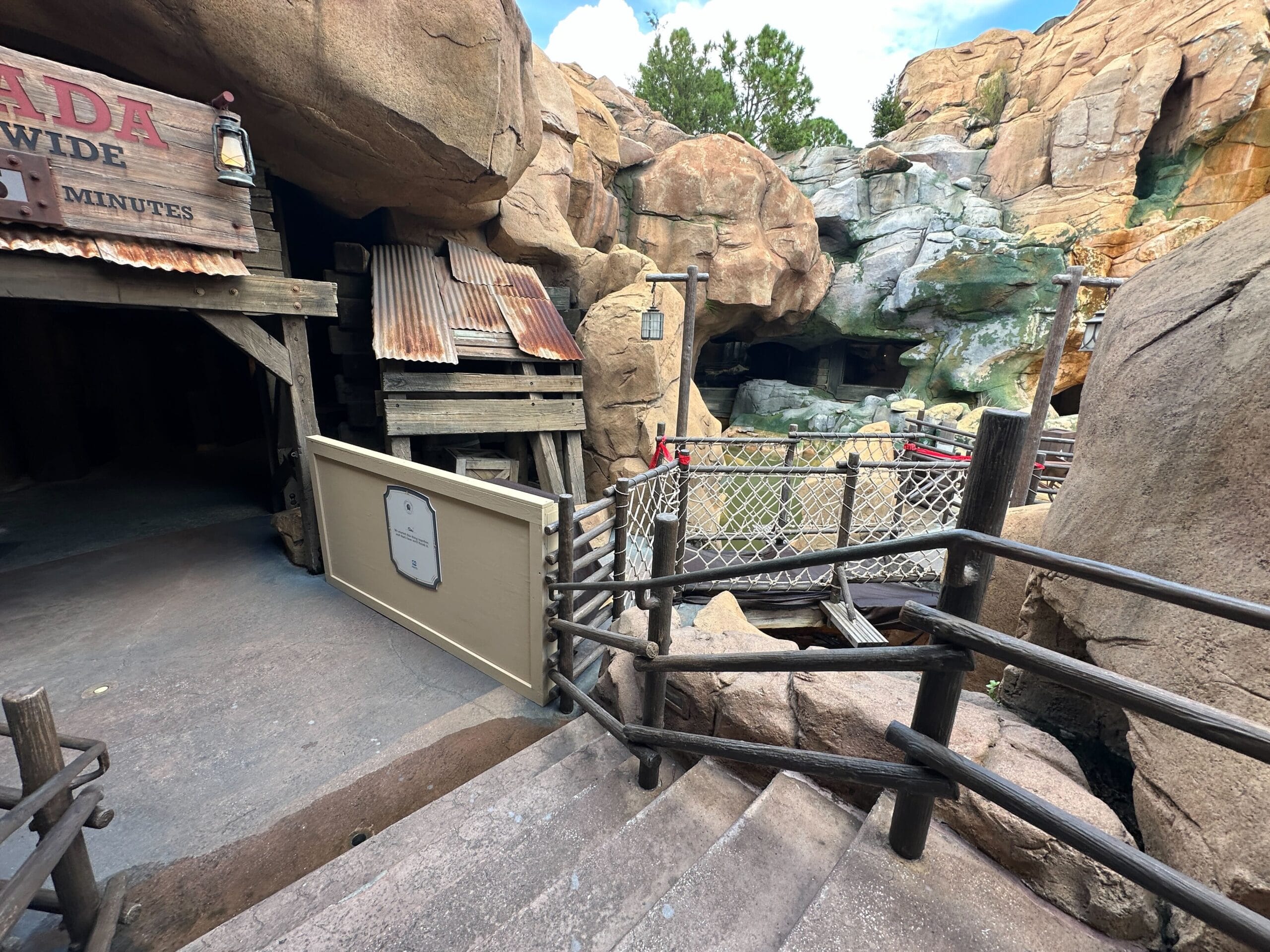 Wooden steps lead to a rustic mining entrance as if awaiting a daily recap on Disney+ in this rocky landscape.
