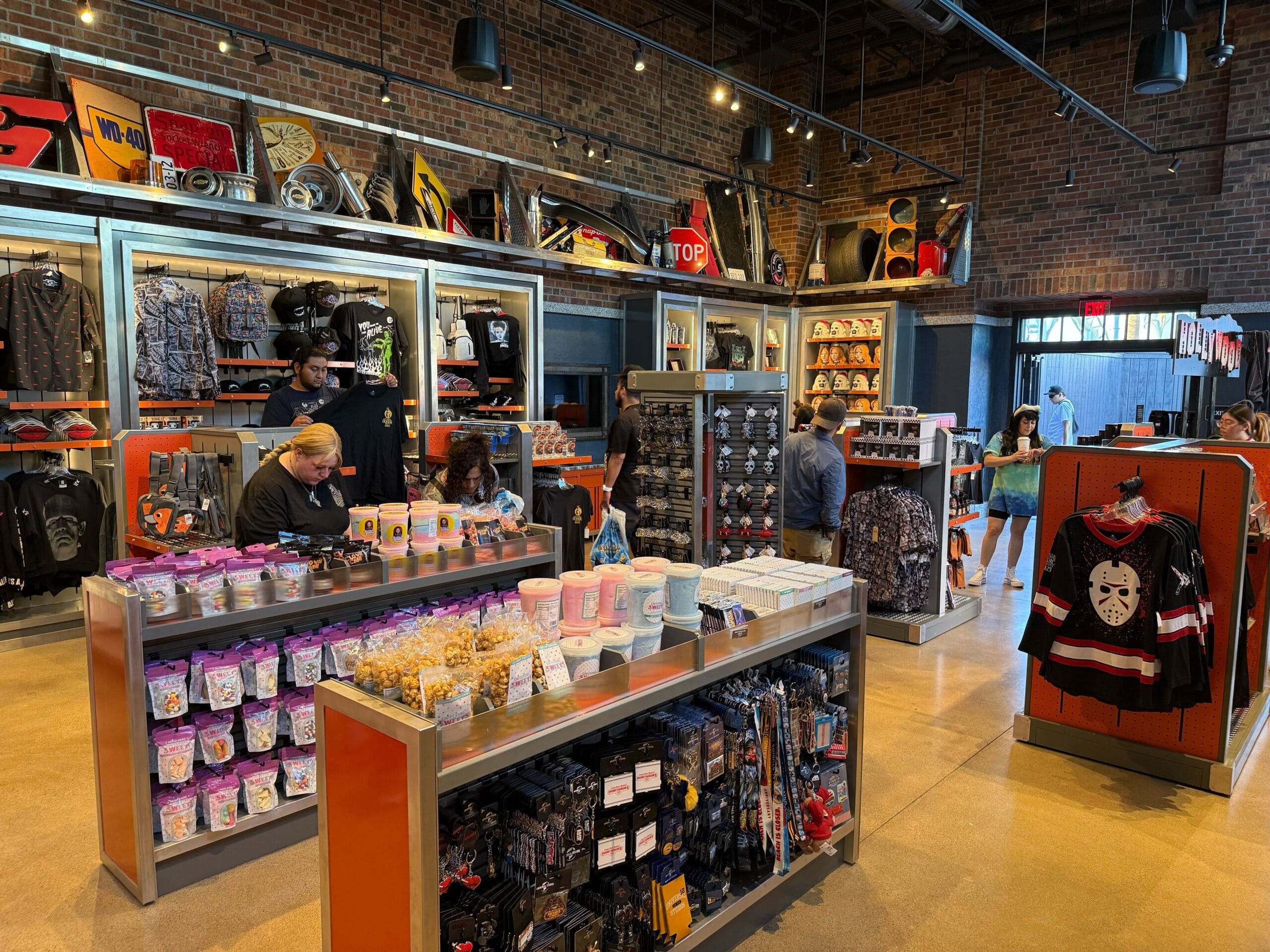 A retail store with people shopping for bags, shirts, snacks, and Fast & Furious merchandise on shelves.