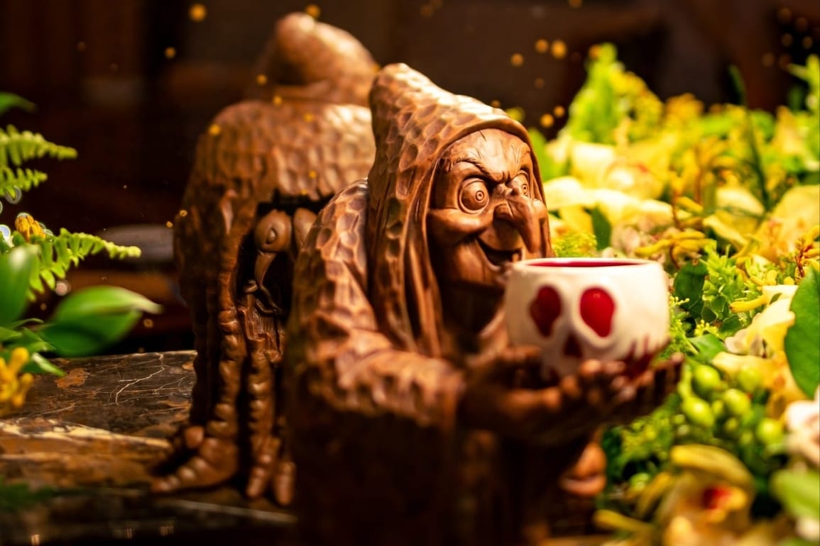 A wooden mug of the Witch from Snow White holding a red poison apple cup.