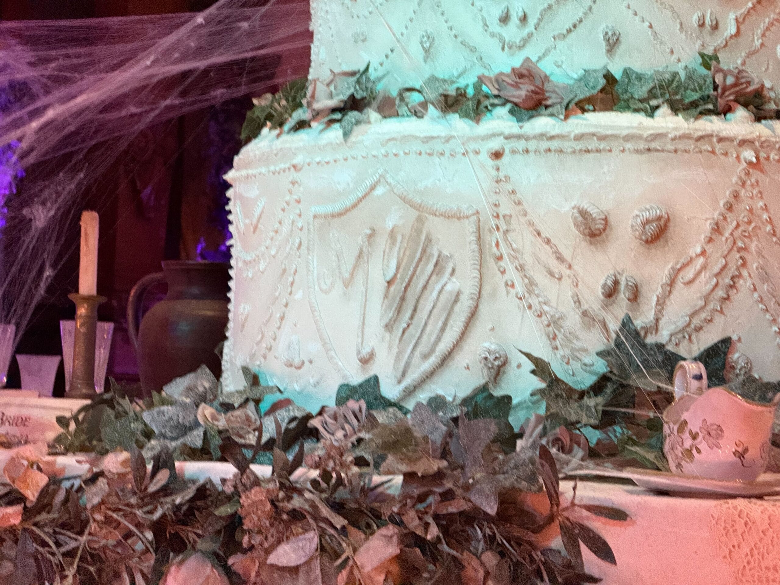 Close-up of a white, ornate cake with shield designs and cobwebs, inspired by Phantom Manor at Disneyland Paris.