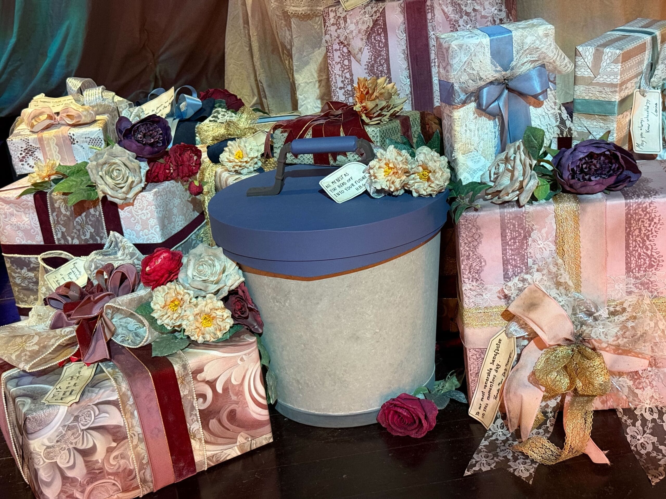 A group of beautifully wrapped presents surrounds a light blue hatbox, hinting at the magic of Disneyland Paris.