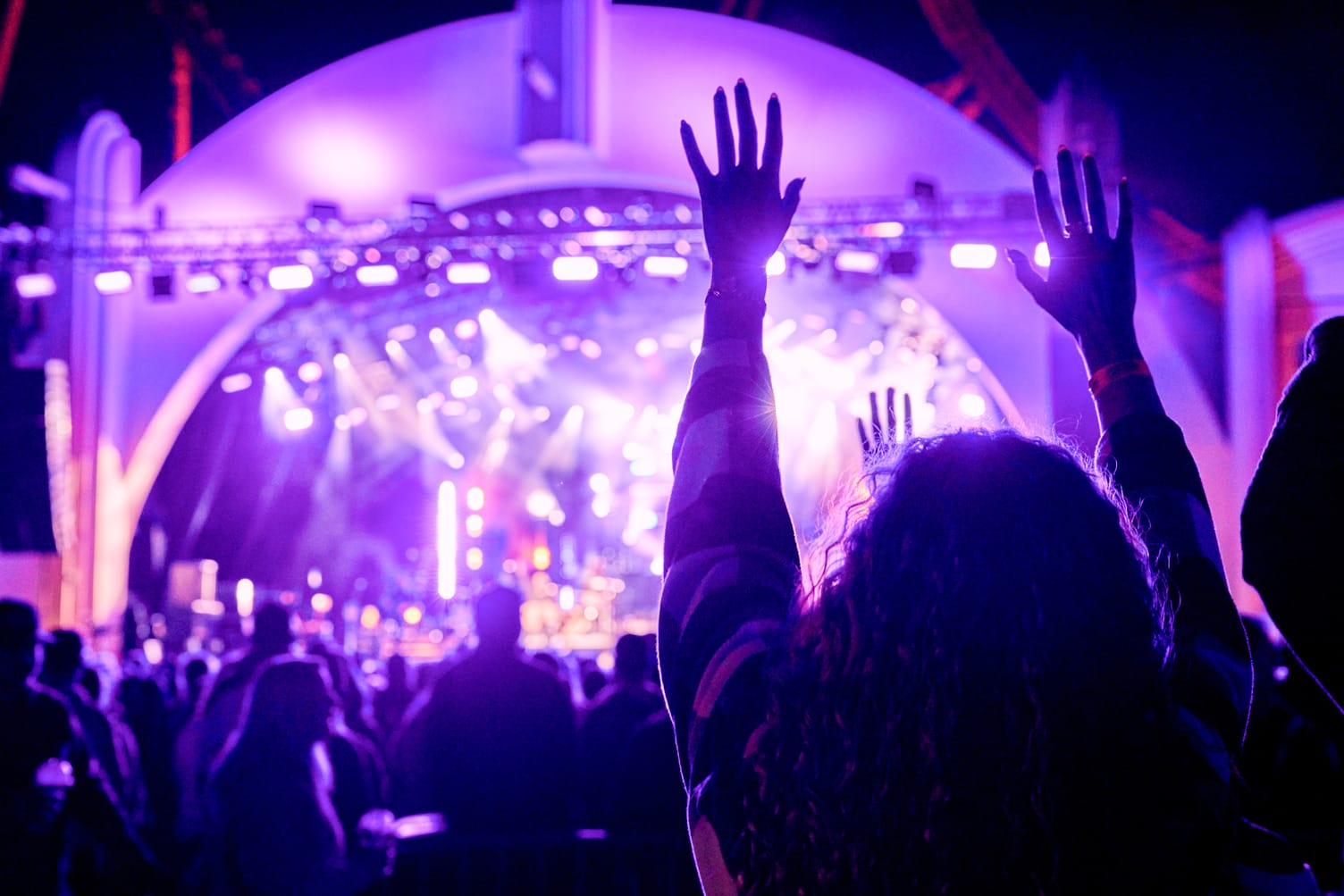 Person with raised hands at Rock the Universe 2026, purple stage lights illuminating the Universal Orlando crowd at night.