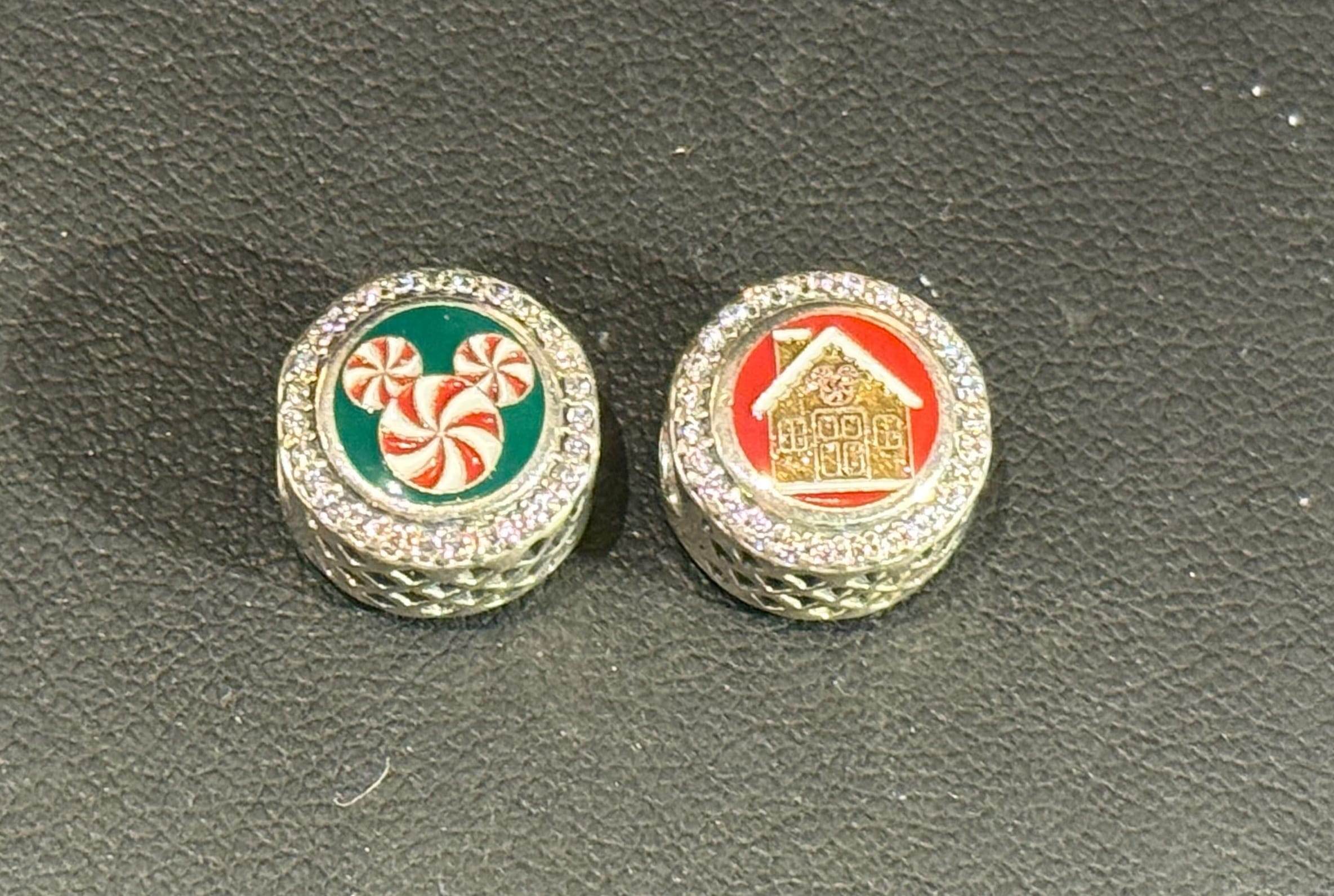Two festive Pandora charms: one with peppermint candies, the other a gold gingerbread house on red, reminiscent of Main Street holiday decor.