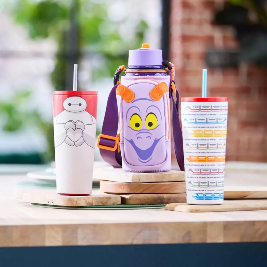 Three Disney character cups, featuring a Figment Water Bottle, on a kitchen counter; background softly blurred for focus.