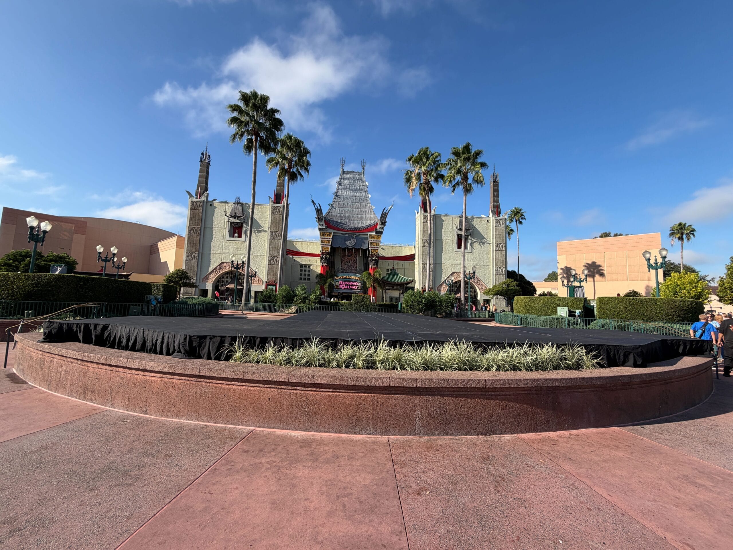 The Chinese Theatre at Disney’s Hollywood Studios lit for Jollywood Nights, palm trees and stage beneath blue sky—no castle in sight.