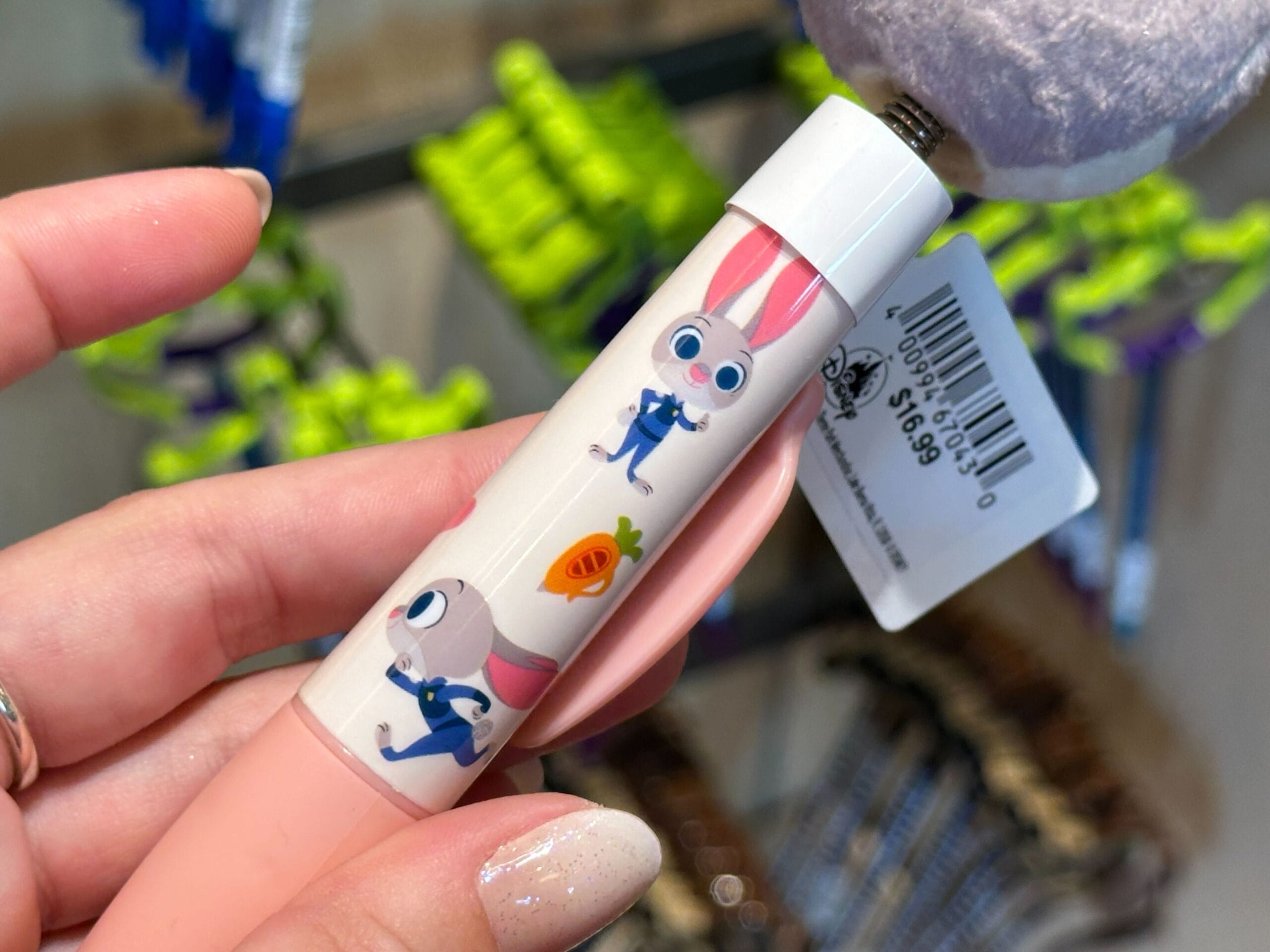 A hand holds a Zootopia Pen with cartoon bunnies and a carrot, just like merchandise found across the Disney Parks; barcode tag attached.