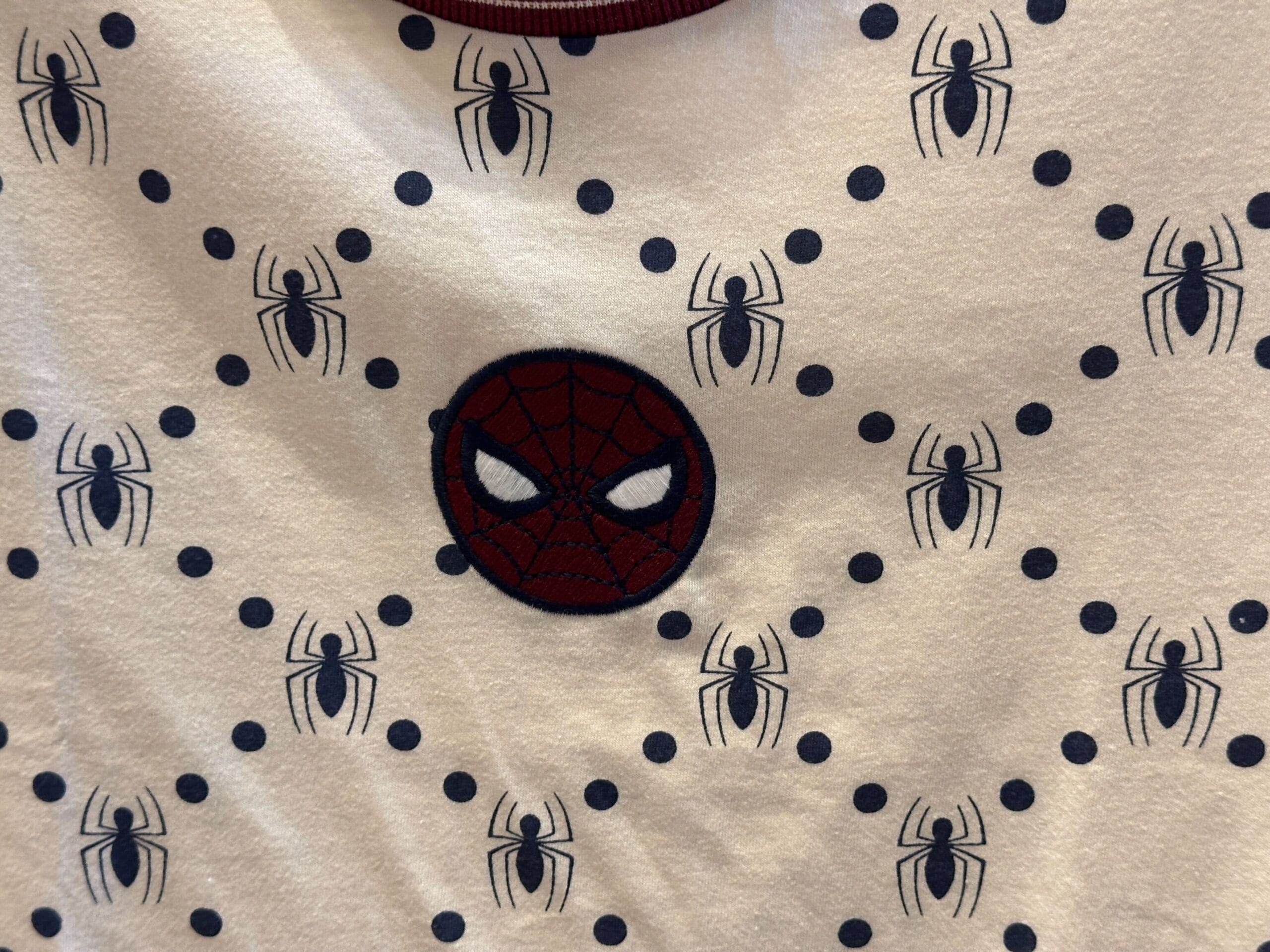 White fabric with black spider-web dots and a central red Spider-Man mask, reminiscent of Marvel spots at Disney California Adventure.