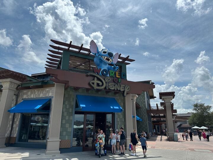 Guests gather outside the World of Disney store, Zootopia pens in front of a giant Stitch statue, under cloudy skies—no castle visible.
