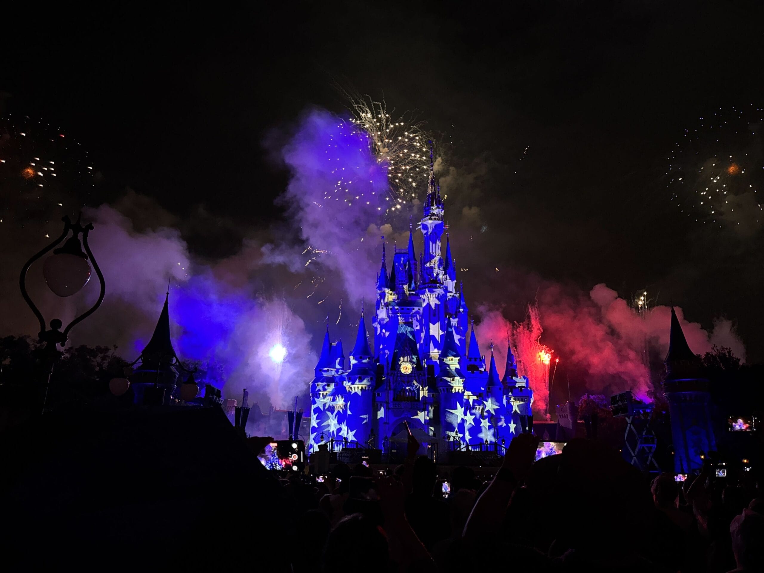 Cinderella Castle at Disney World glows blue amid fireworks, its iconic spires distinct from Sleeping Beauty Castles worldwide.