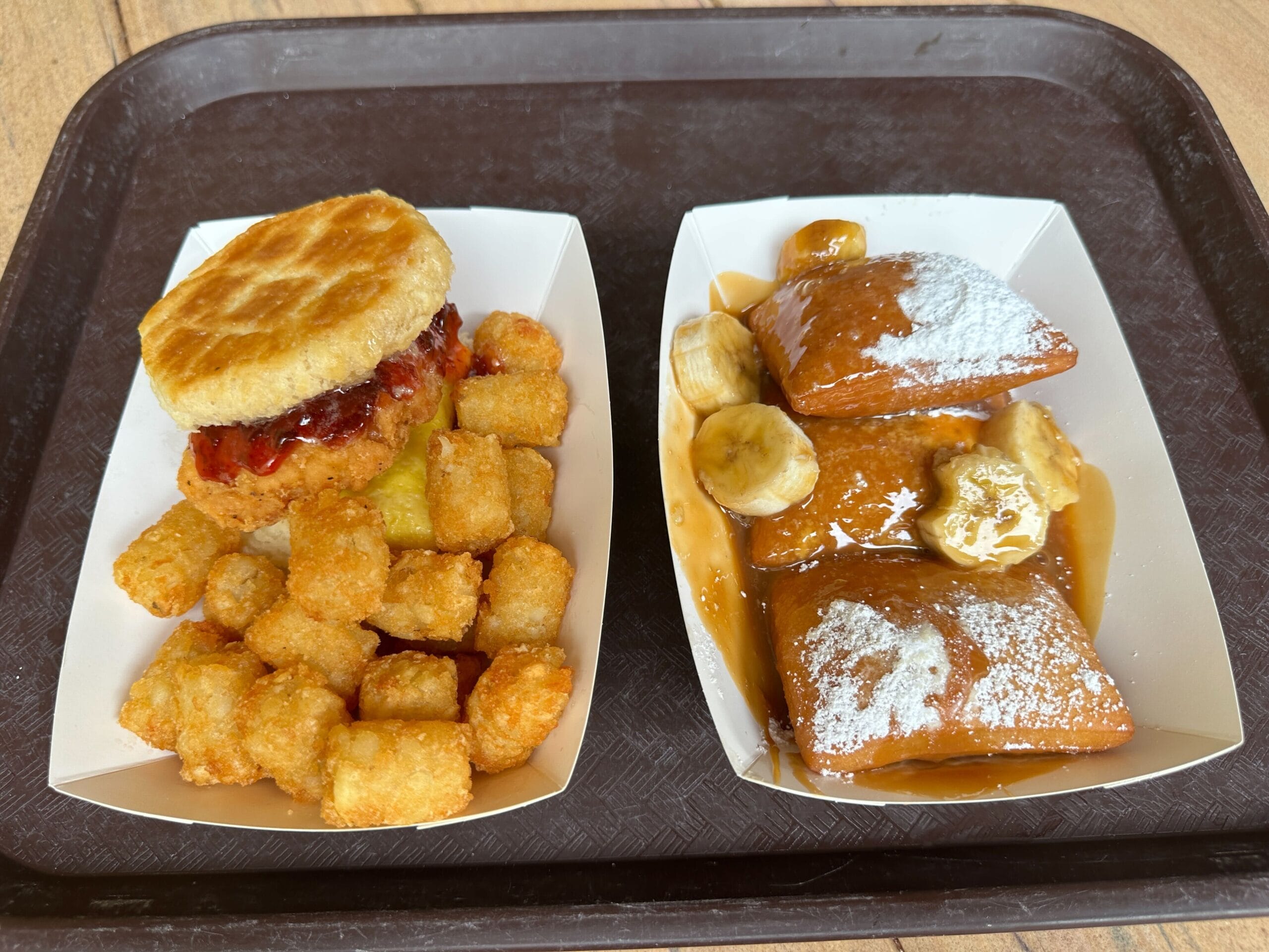 Golden Oak Outpost breakfast tray with tater tots, chicken biscuit, and beignets, capturing Magic Kingdom’s unique morning fare.