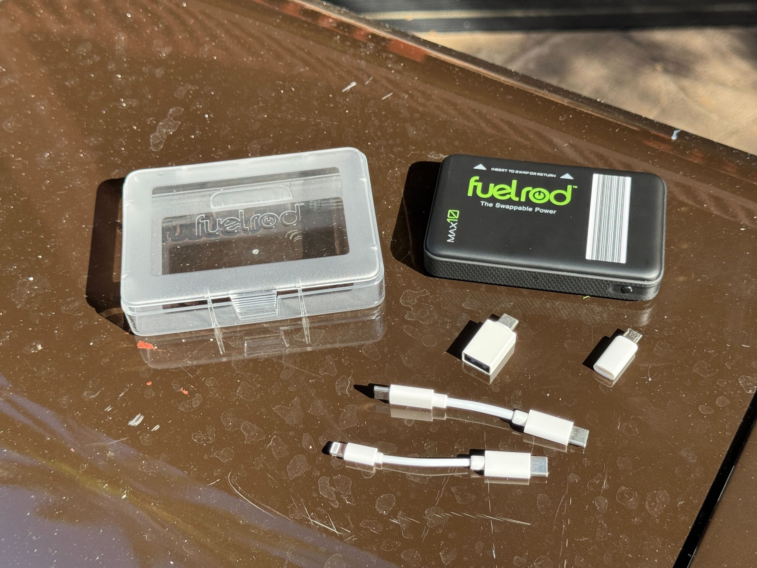 A FuelRod power bank and adapters in bright sunlight, ideal for powering up at Walt Disney World near Cinderella Castle.