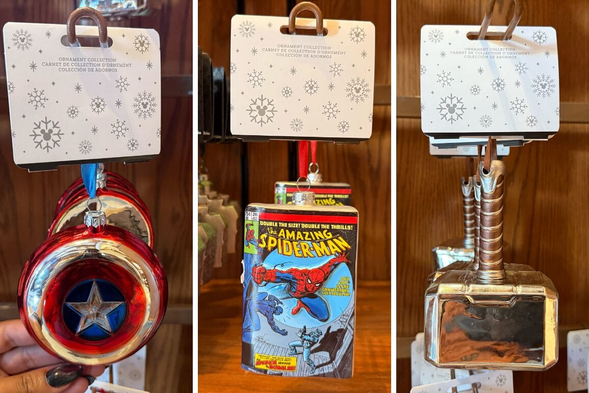 Three Marvel-themed ornaments—Captain America's shield, a Spider-Man comic, and Thor's hammer—hang on display hooks, similar to Disney Parks souvenir displays.