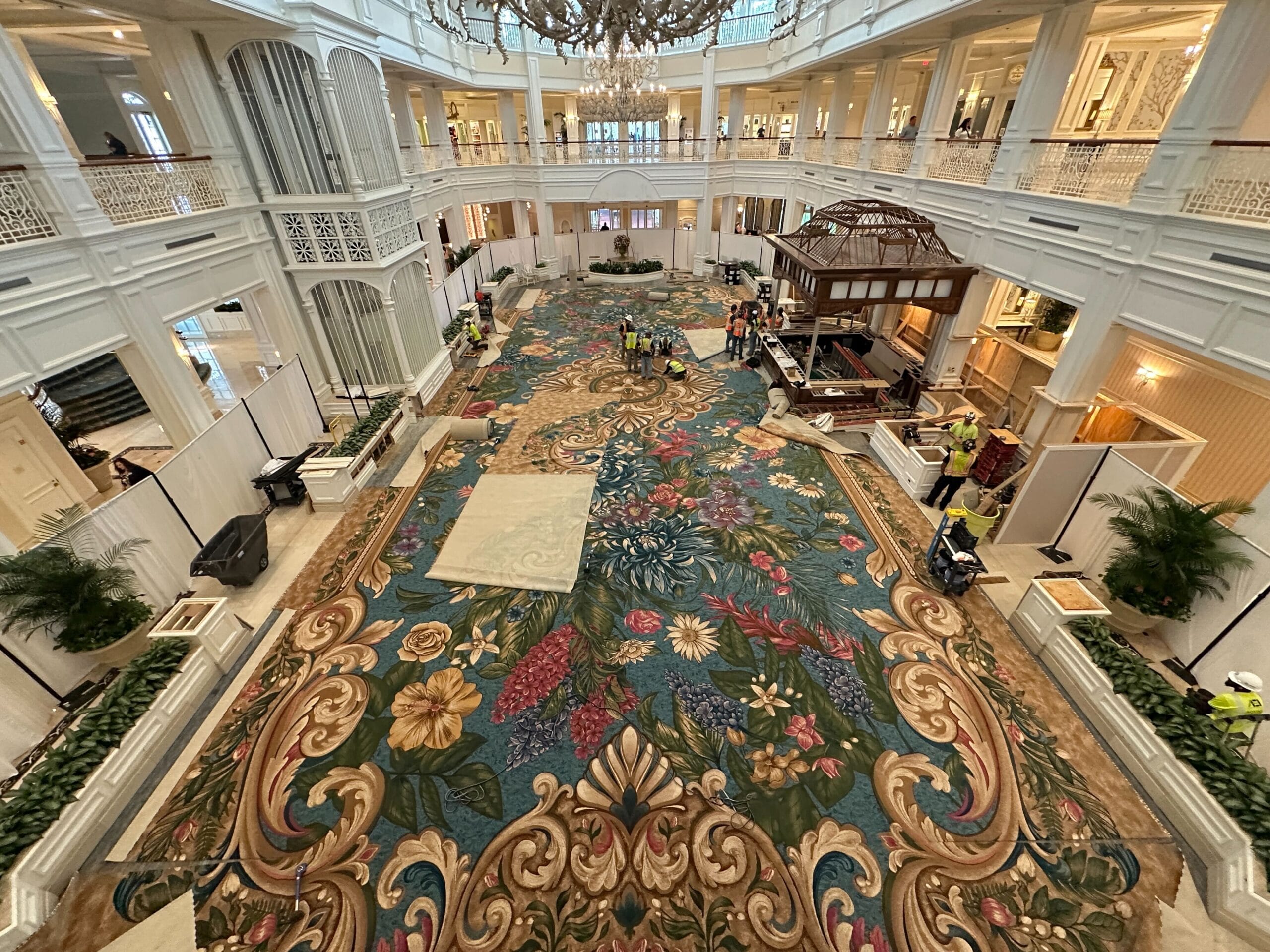 Crew and tools fill the elegant Grand Floridian lobby on lively floral carpet—Disney World’s Victorian grandeur, no castle visible.