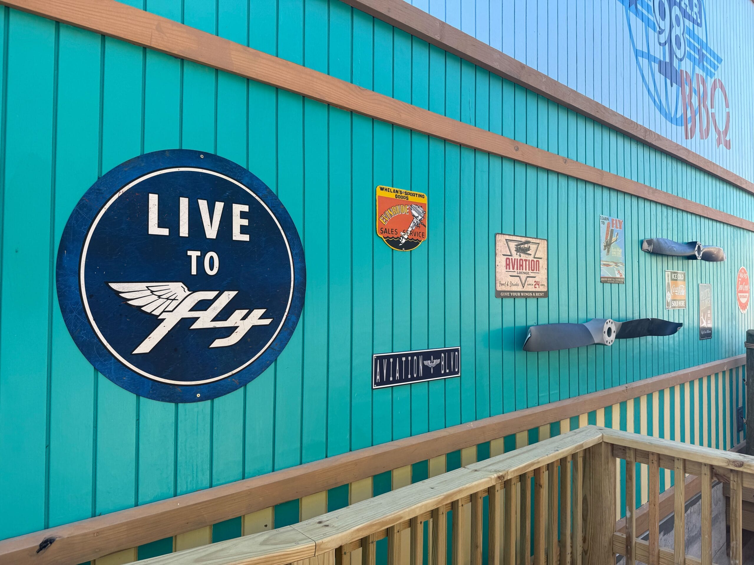 Aviation-themed props are along the outside of the building and inside. There are old metal signs and propellors mounted on the walls.