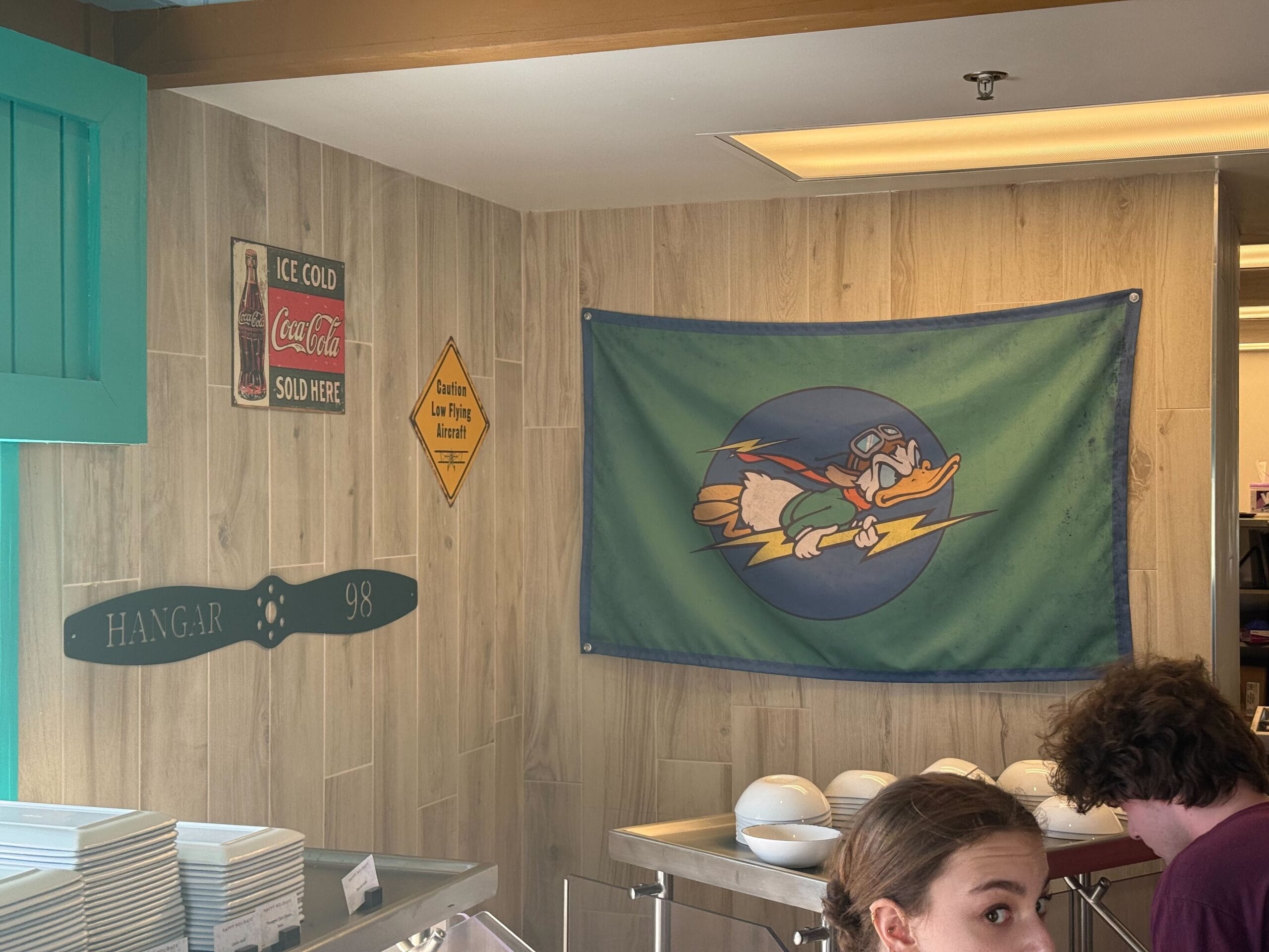 A Castaway Air flag hangs by the kitchen. It features Donald Duck in an aviator helmet and goggles, flying with a lightning bolt in his hands.