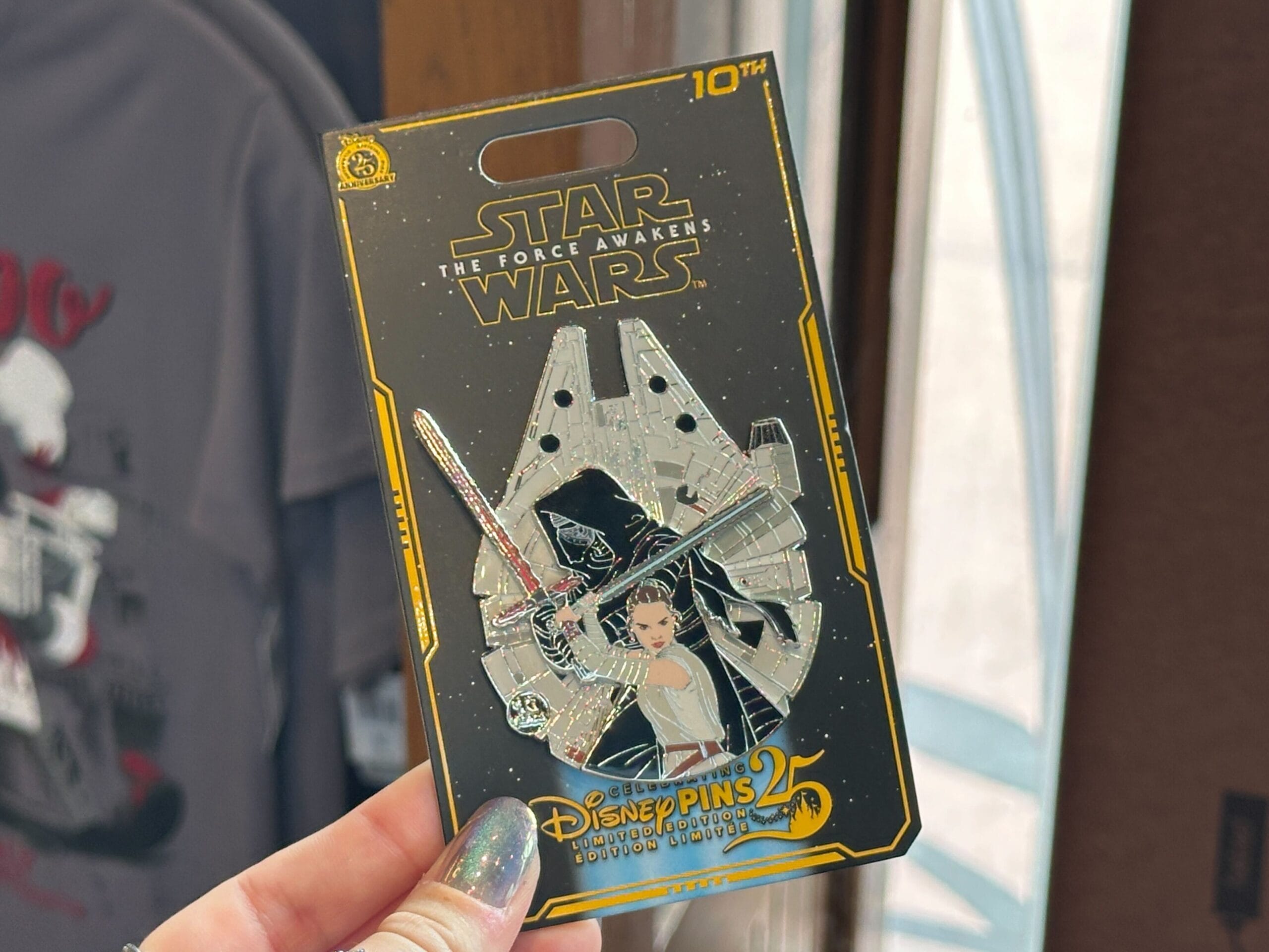 The larger of the two Force Awakens pins depicts Rey with the blue lightsaber and Kylo Ren with his red saber, set against the Millennium Falcon.