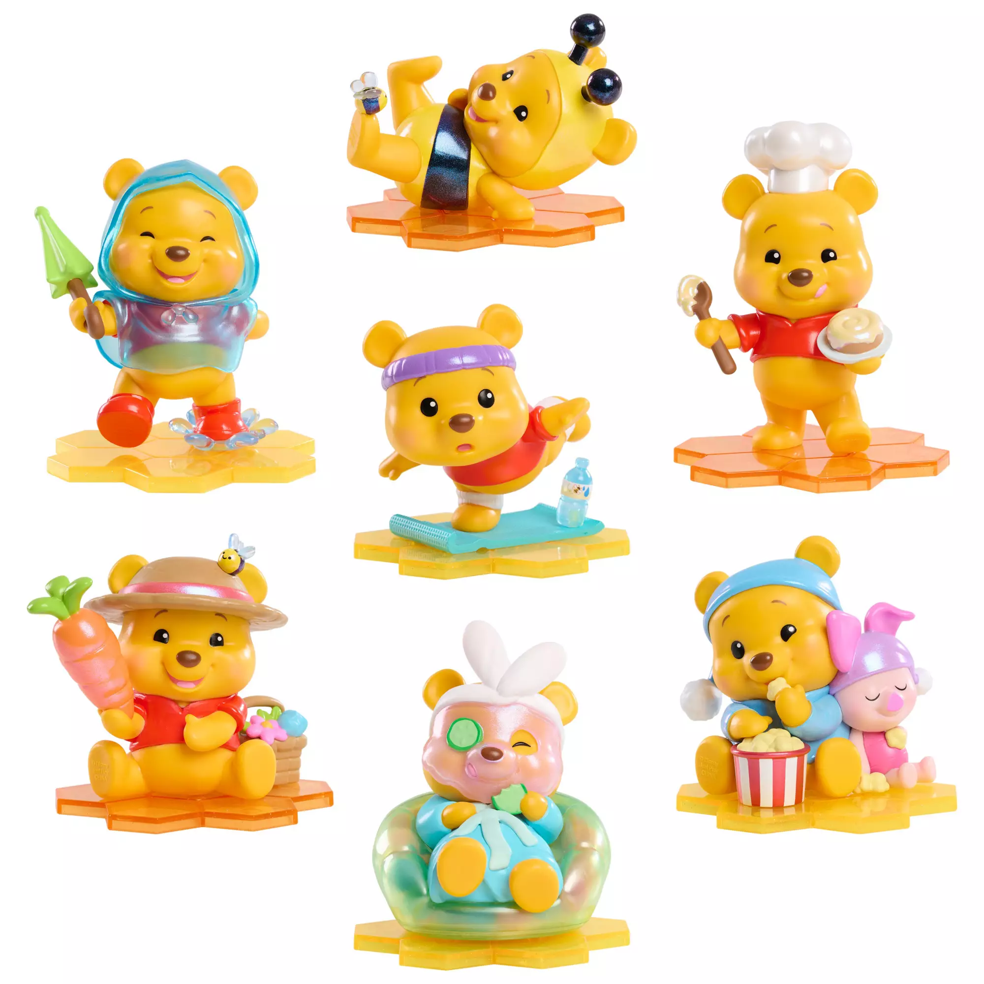 This set contains one mystery Winnie the Pooh figurine in each blind box. The options include Winnie the Pooh dressed as a bee, wearing a rain jacket, doing yoga, baking a dessert, farming vegetables, having a spa day, and eating popcorn with Piglet. Each figurine snaps onto a glittery honeycomb base.