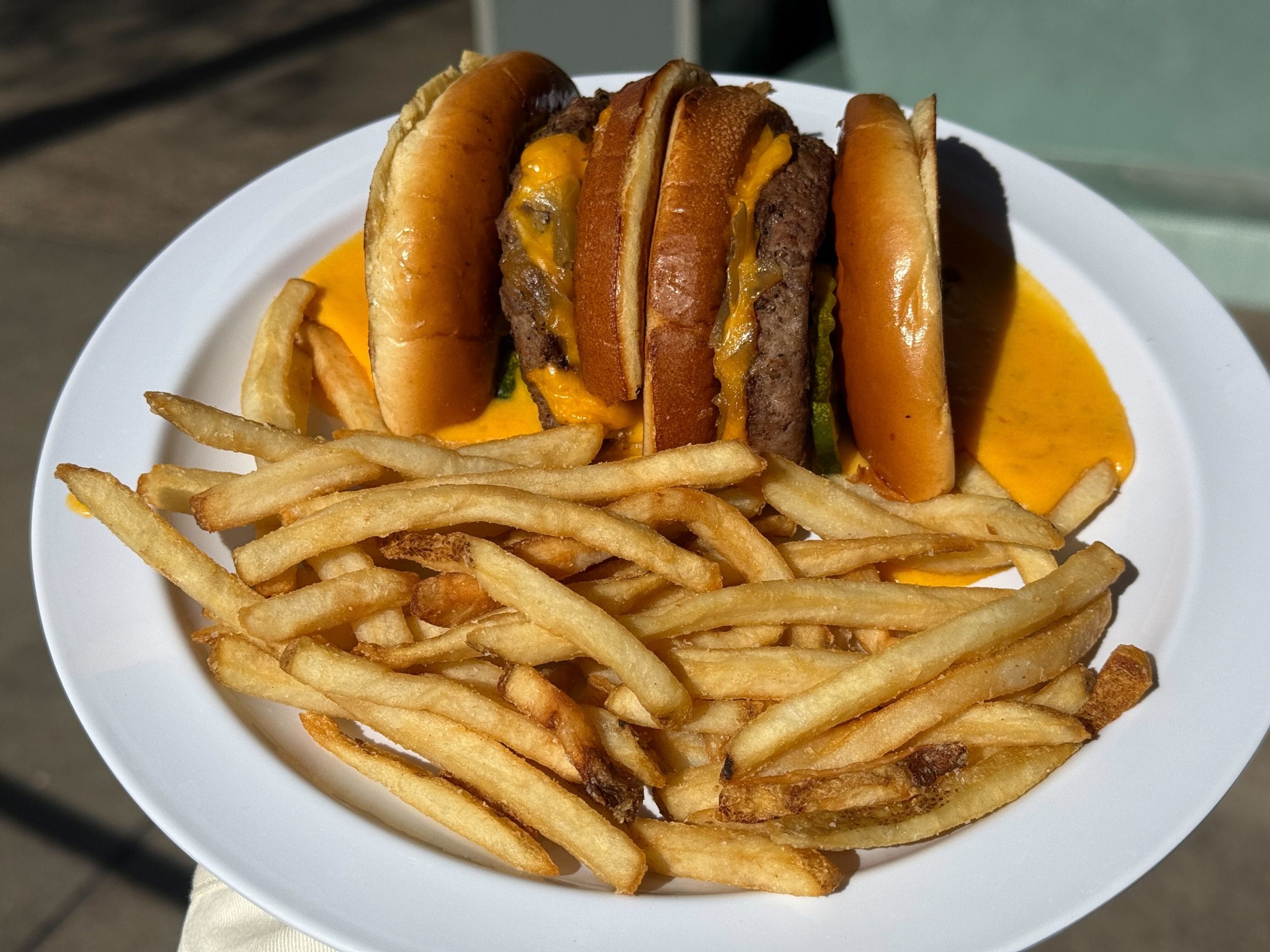 Beef patty, American cheese, B&B pickles, and caramelized onions on a toasted bun with pepperoncini cheese sauce served with fries