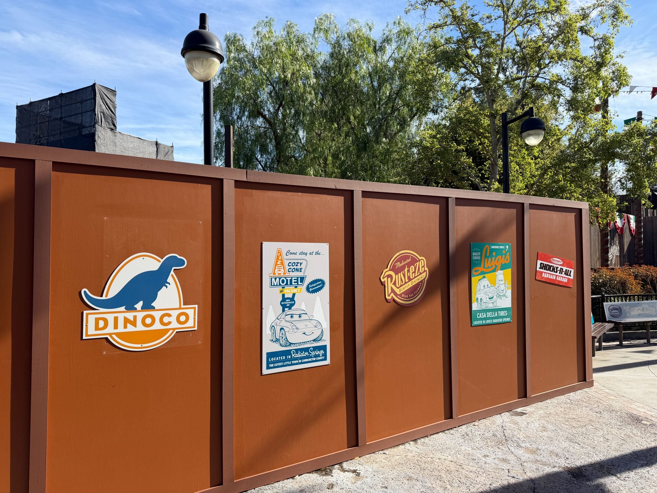 Construction walls adorned with Cars-themed Marvel parody posters on the walkway between Cars Land and Avengers Campus in Disney California Adventure