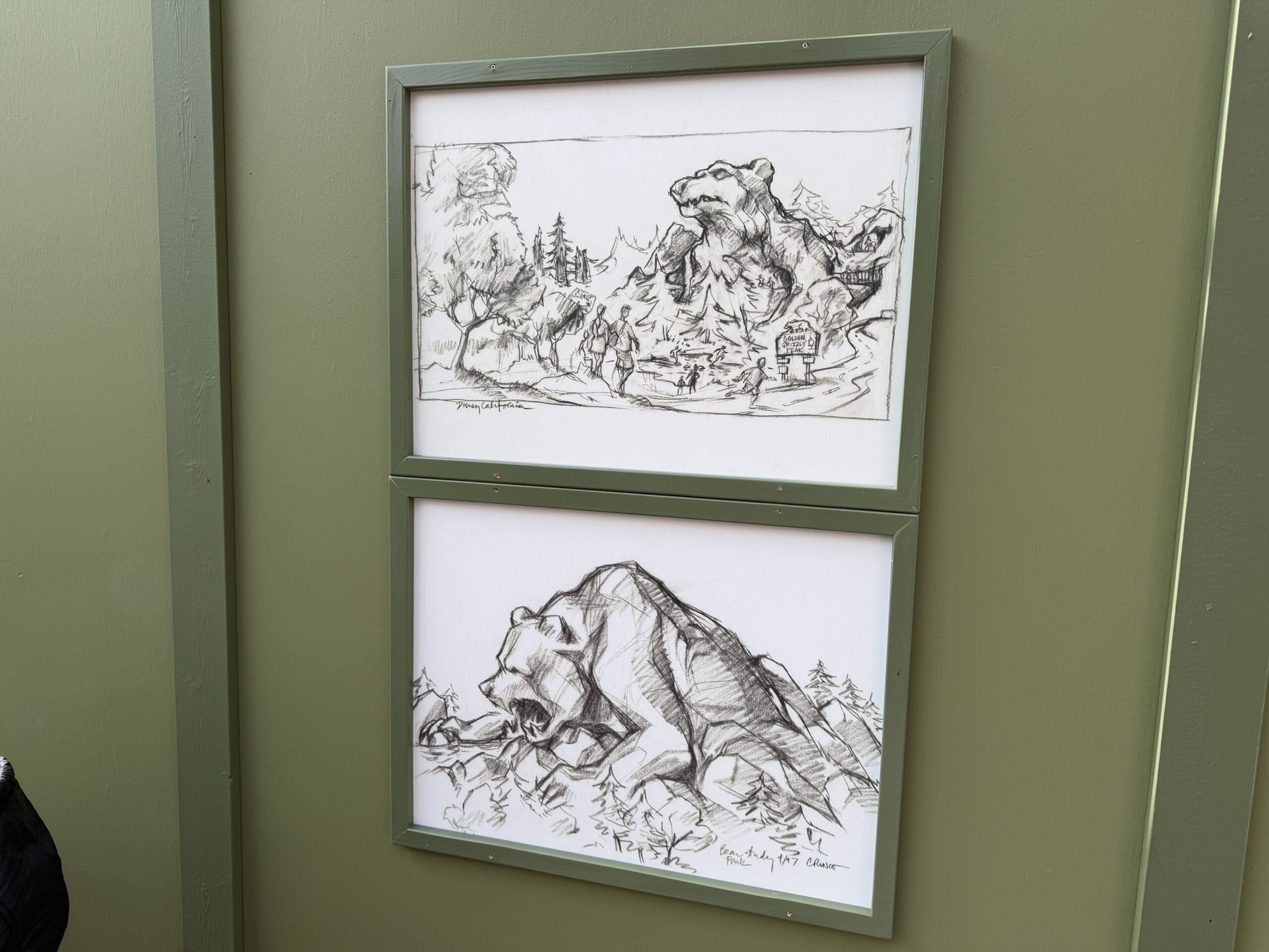 Another set of framed artworks show black-and-white sketches of concept art for early designs of Grizzly Peak. The mountain shows more parts of a grizzly bear, like the legs. It also appears to say "97" in the corner of one artwork, suggesting the concept art was created in 1997.