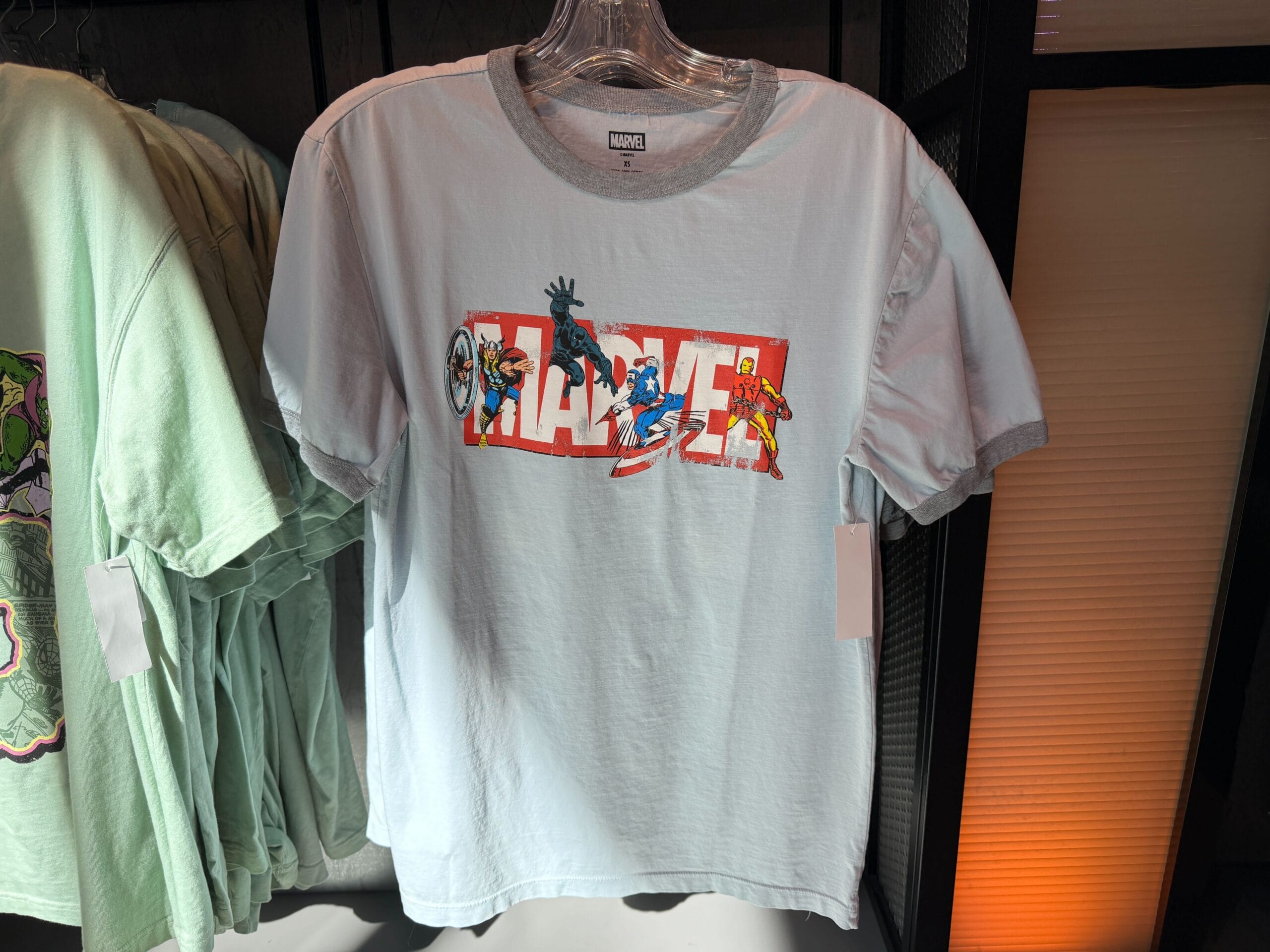 This light grey adult t-shirt features the classic red and white Marvel logo with four different heroes interspersed in it.