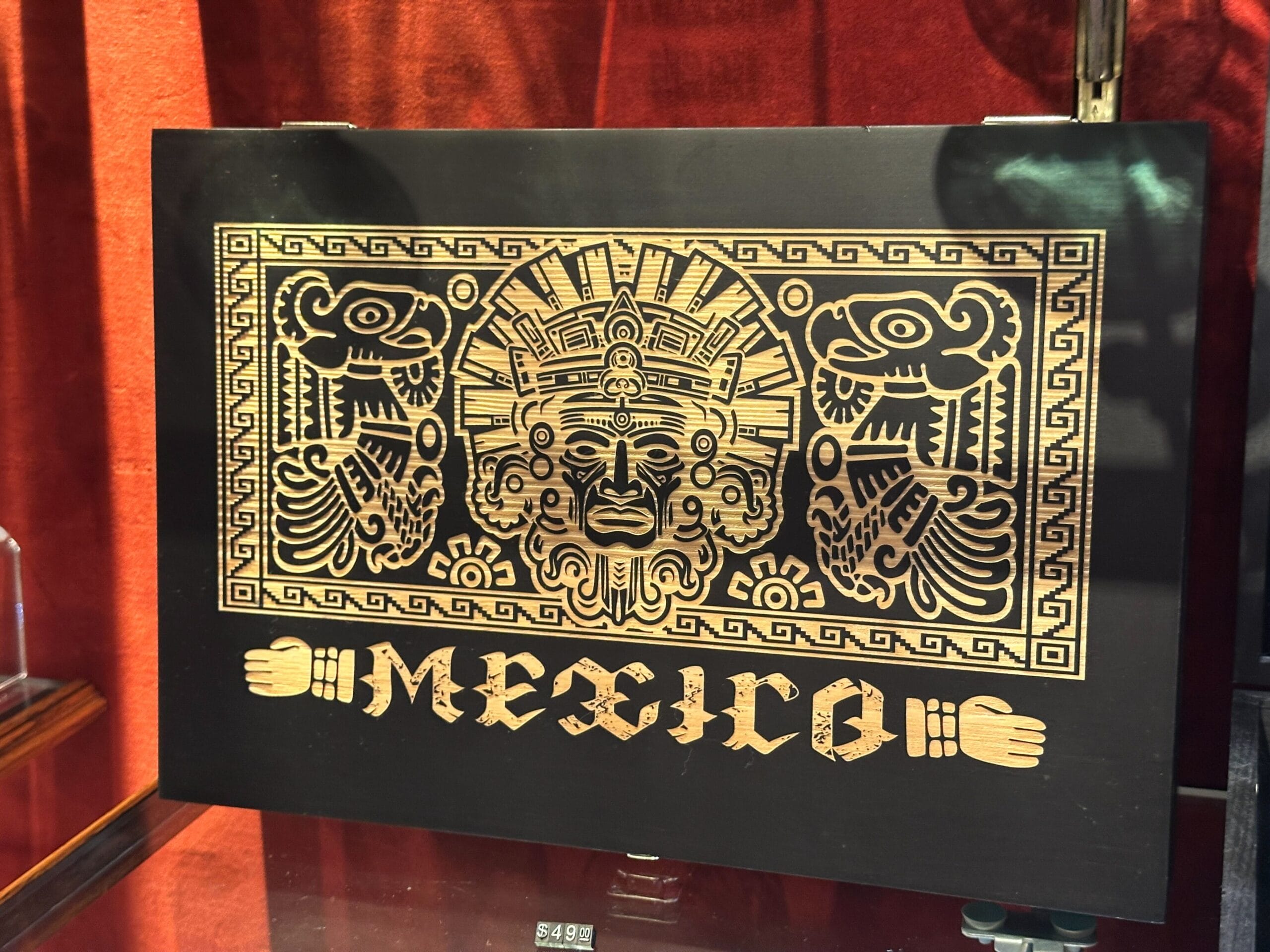 The front of the boxes also features artistic etchings. This black display box has the word "Mexico" at the bottom and has several Aztec symbols.