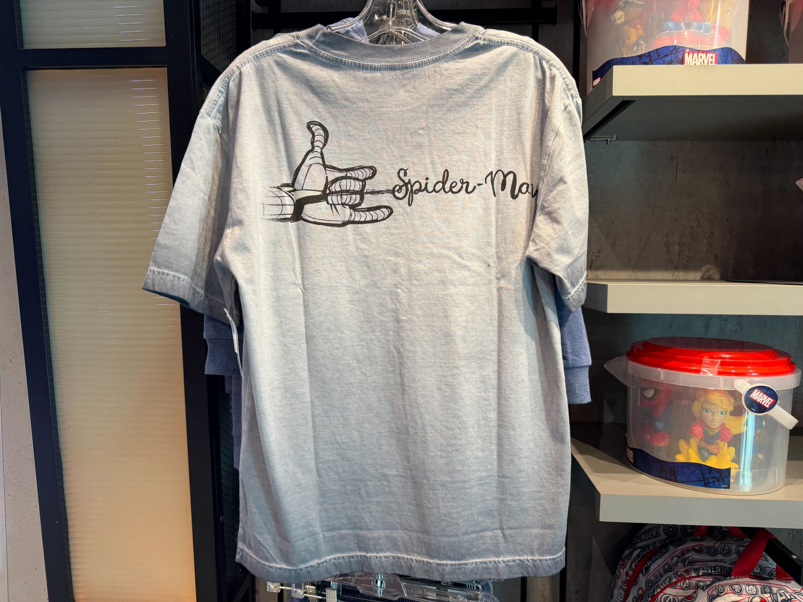 On the back of the shirt is a black sketch design of Spider-Man's hand shooting a web, which spells out "Spider-Man" in a cursive font.