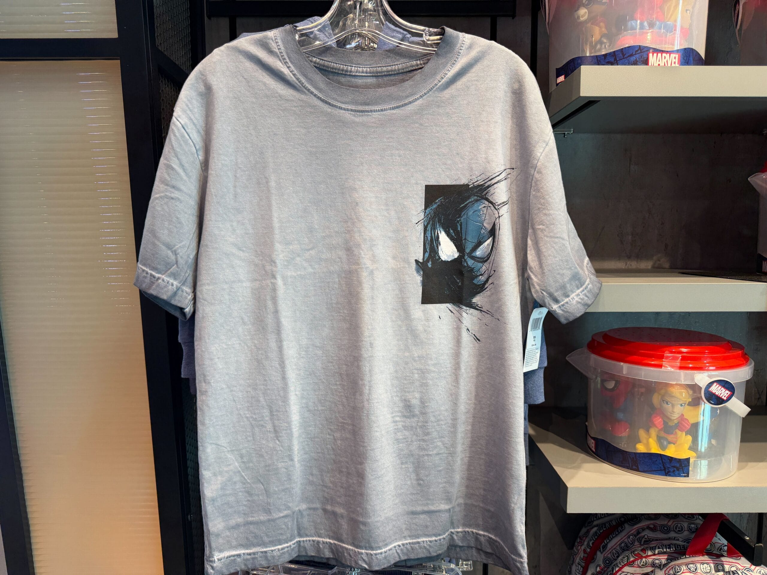 This grey adult t-shirt has an image on the right chest. It appears to be a split mask design between Spider-Man and Klyntar or a symbiote.