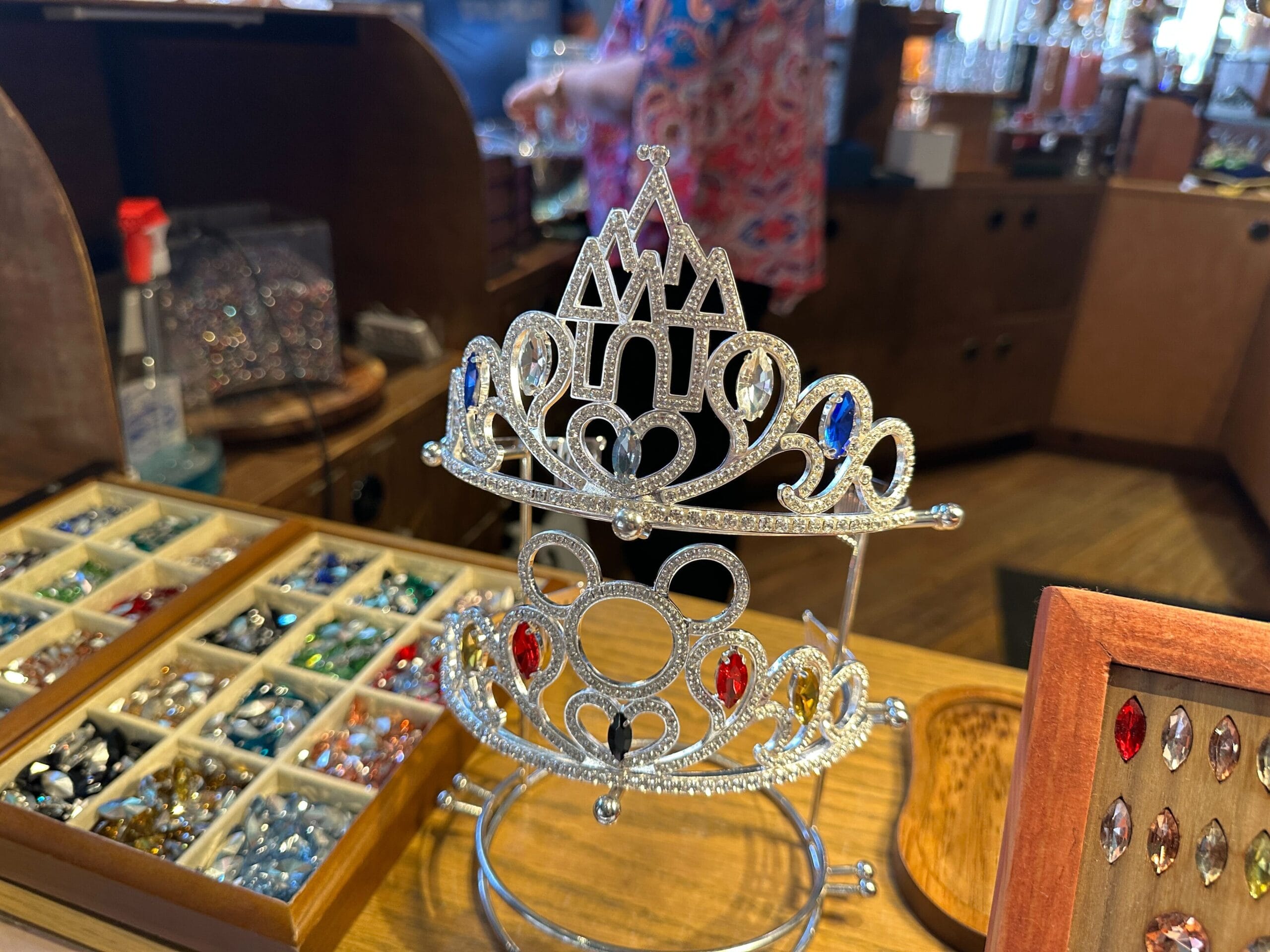 To design your own tiara, Cast Members help you choose your pieces and put everything together. Each tiara consists of a sterling silver base bedazzled with clear rhinestones with spots for five gemstones of your choice. There are dozens of colorful jewels to choose from.