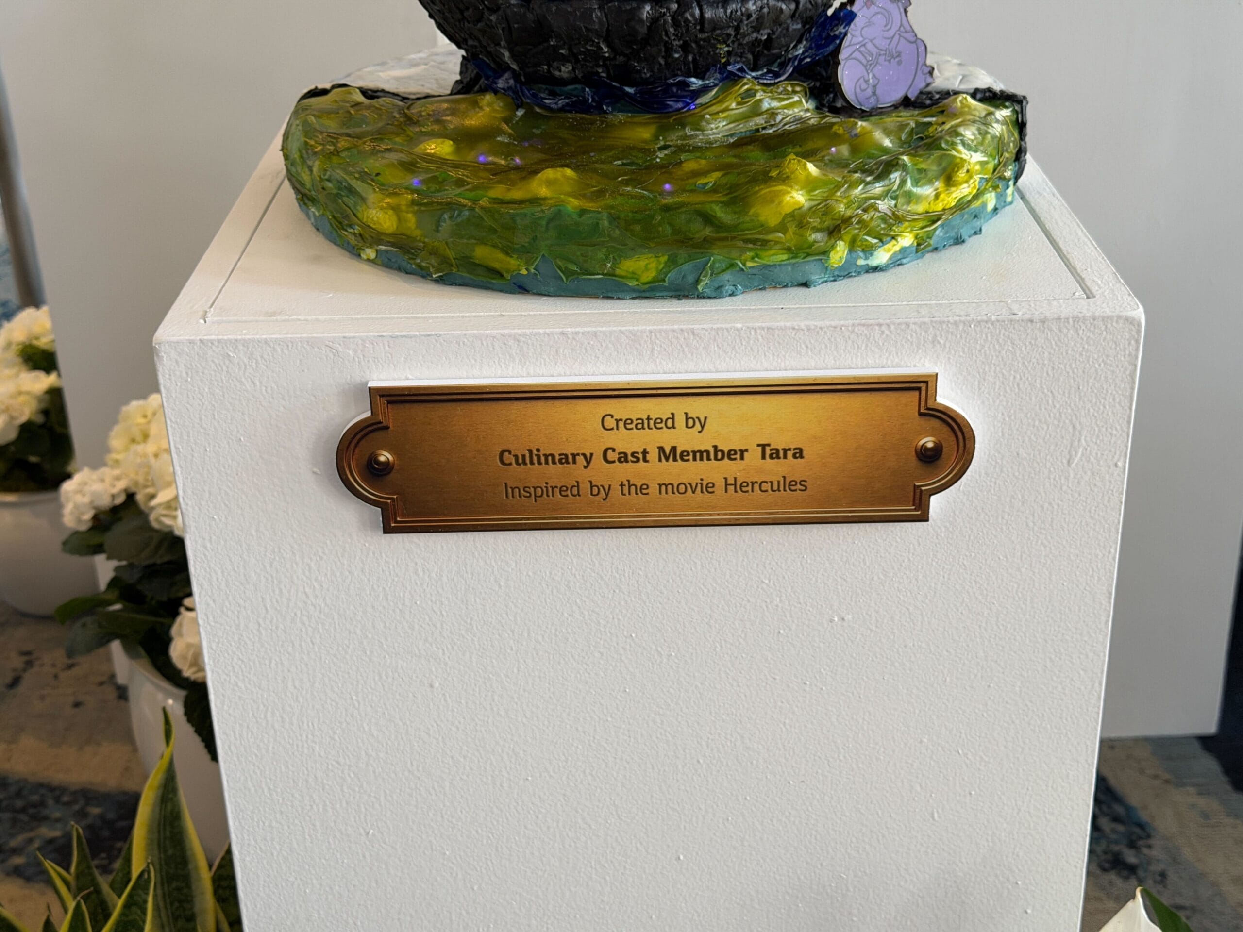 The back of the egg has a painted picture of Megara sitting on top of a bench. The muses are represented on the bench as Megara holds a white flower as a reference to 'I won't say I'm in love.'