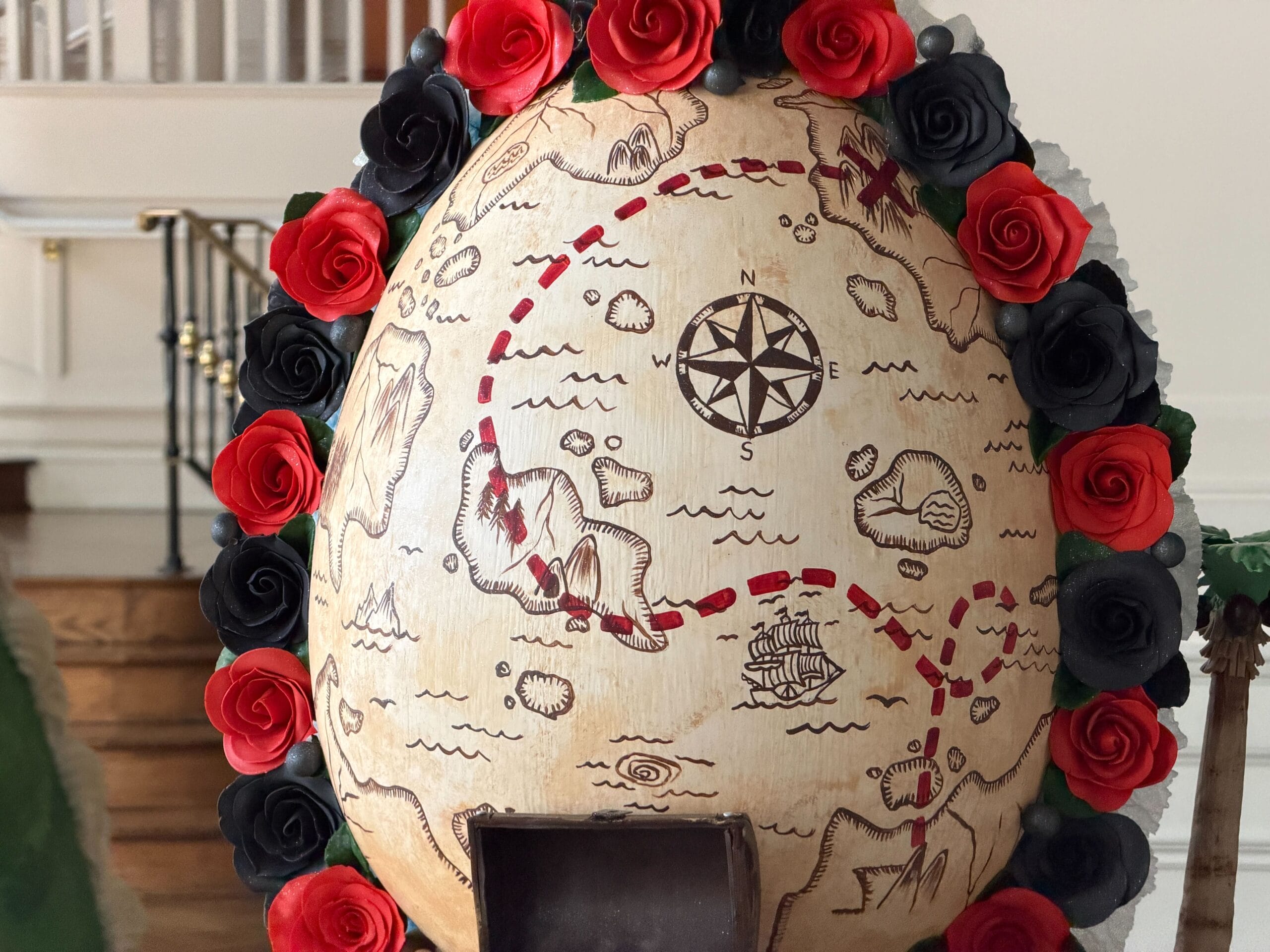 The back of the egg has a treasure map surrounded by red and black roses. A treasure chest stands on the bottom with coins and balls.