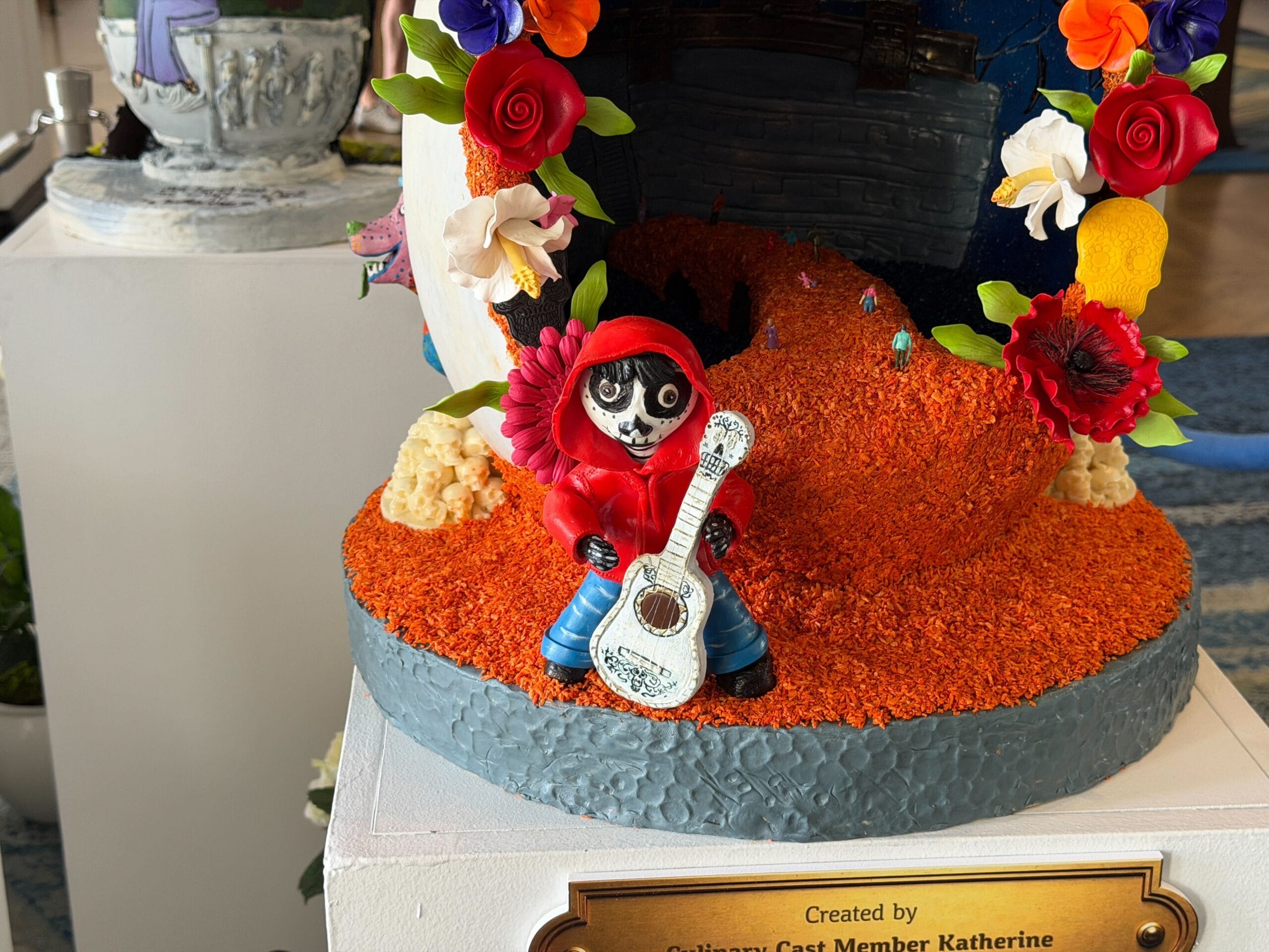 The first egg is inspired by Pixar's 'Coco'. Flowers decorate the hollow interior of the egg as the inside is sculpted to resemble the Marigold Bridge, with the Land of the Dead visible behind it. Bienvenidos is written above the building in purple. The Bridge even has little people crossing it.