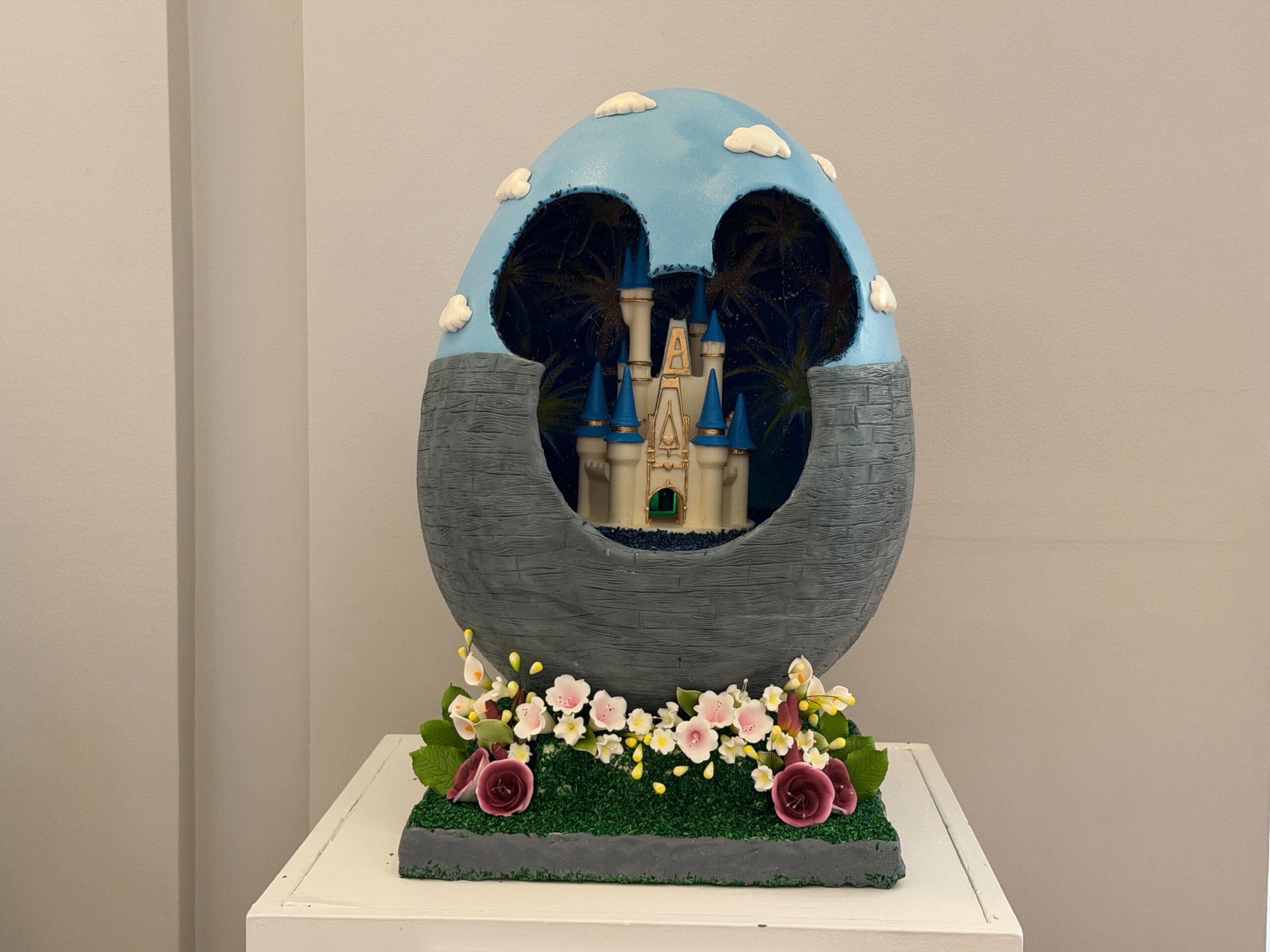 The last of these eggs features Cinderella Castle inside a hollow egg. The bottom half is patterned with bricks, while the top half resembles a sky. Flowers adorn the base. The castle appears to have its old color scheme, which is being slowly restored on the real thing.