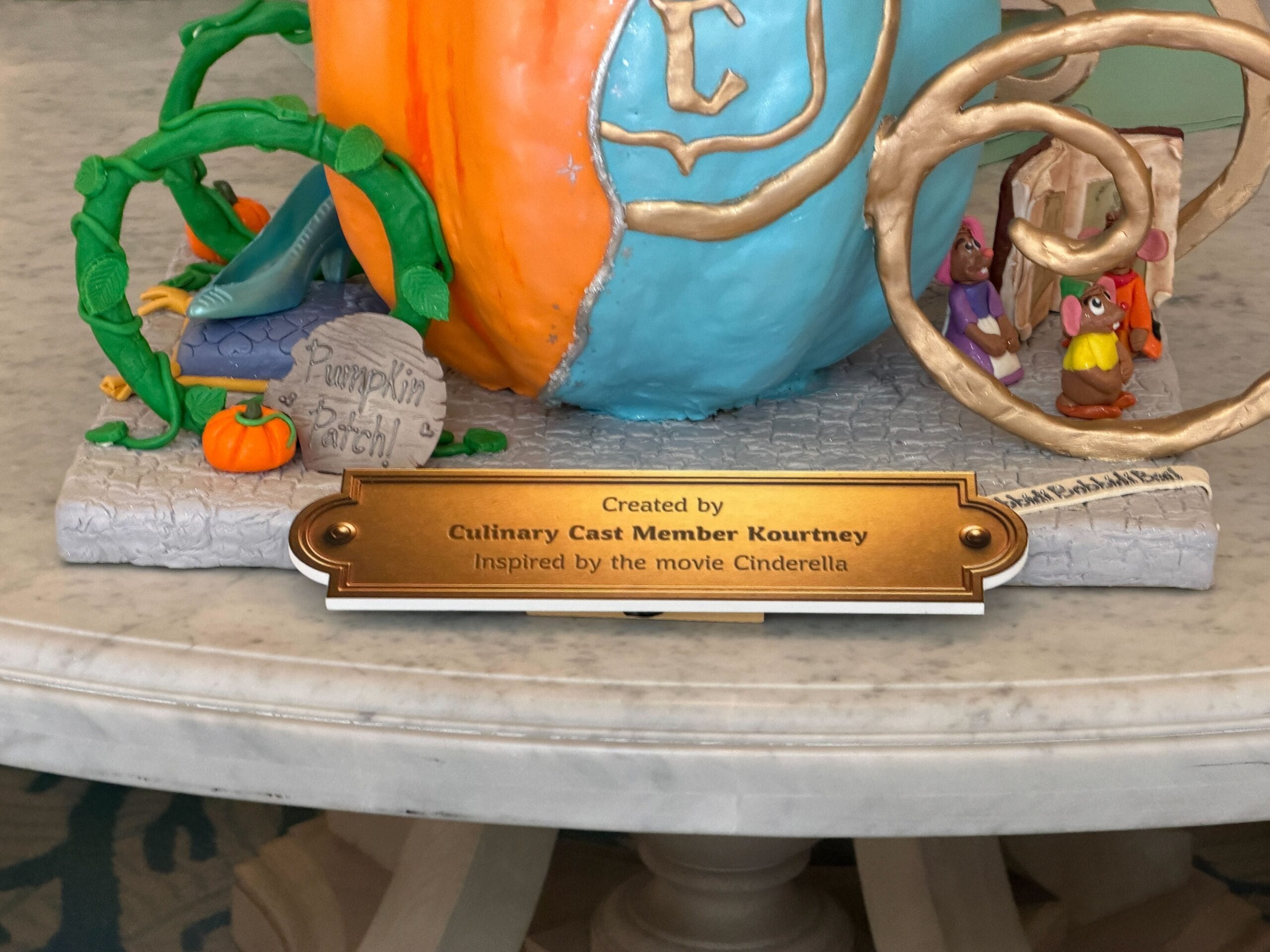 Jaqcues, Gus, and Mary, the mice from the film, as they are reading the book from which they make Cinderella's dress. Bibbity Bobbity Boo! is written on the ground, while another sign reads Pumpkin Patch! next to the glass slipper sitting on a pillow.