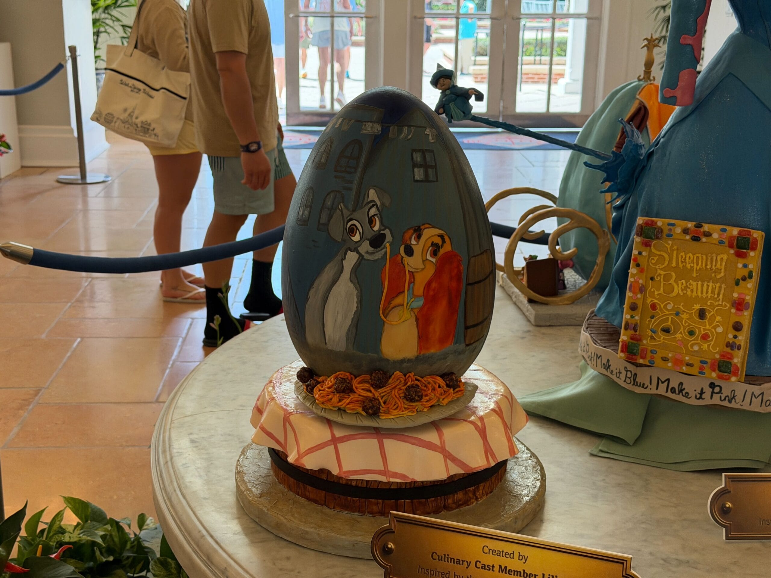 The egg, inspired by Lady and the Tramp, has the base of the table at Tony's restaurant, with the spaghetti and meatballs serving as a way to hold up the egg. The egg itself has a painted display of the shot where Lady and the Tramp eat the spaghetti in the alley.