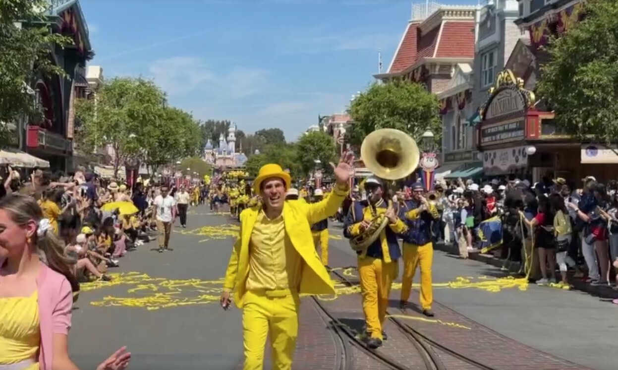 Performers and live musicians dressed in yellow follow behind with yellow streamers.