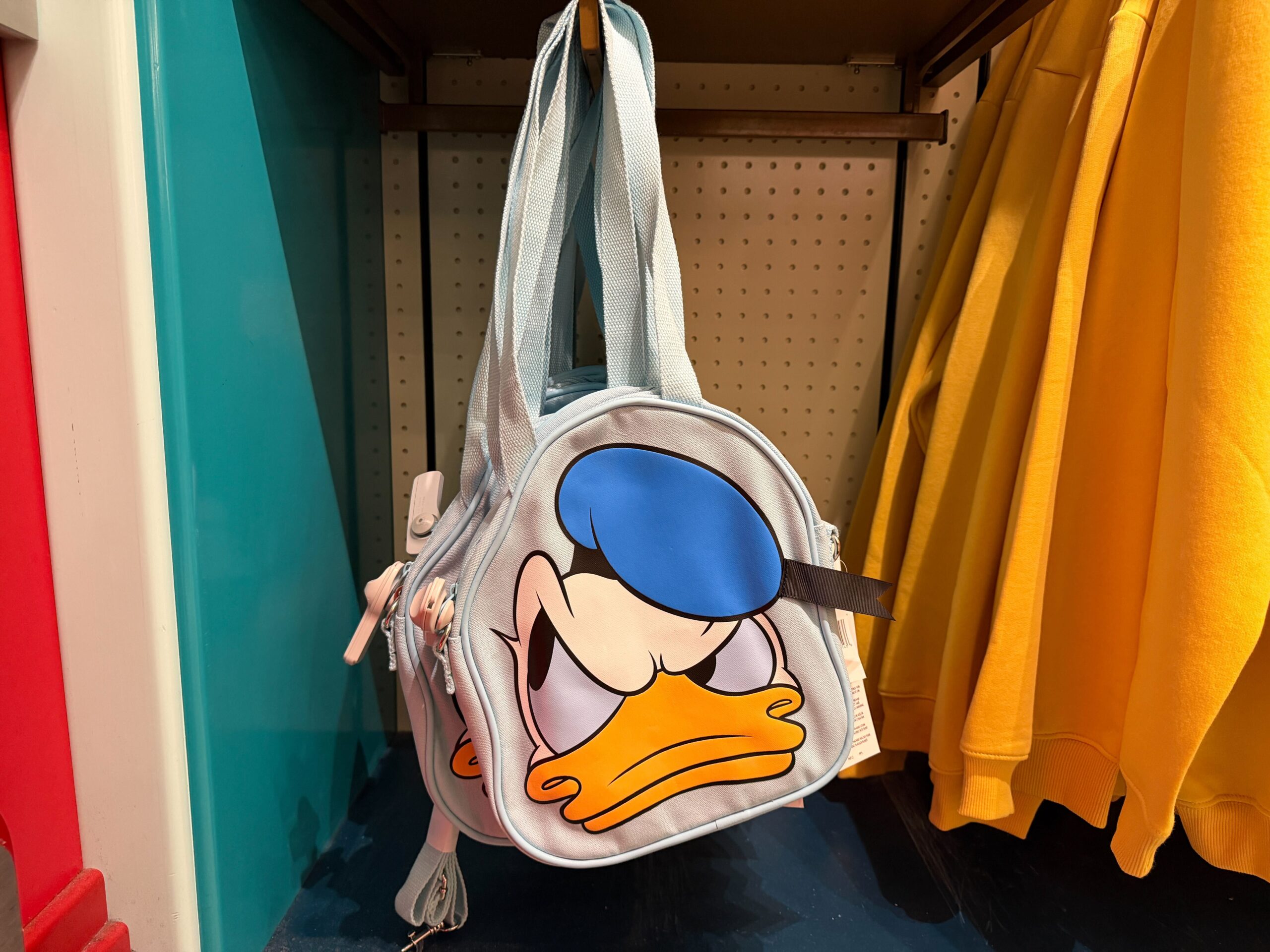 The Donald tote is light blue with his face printed on one side. It also has two shoulder straps and a detachable crossbody strap.